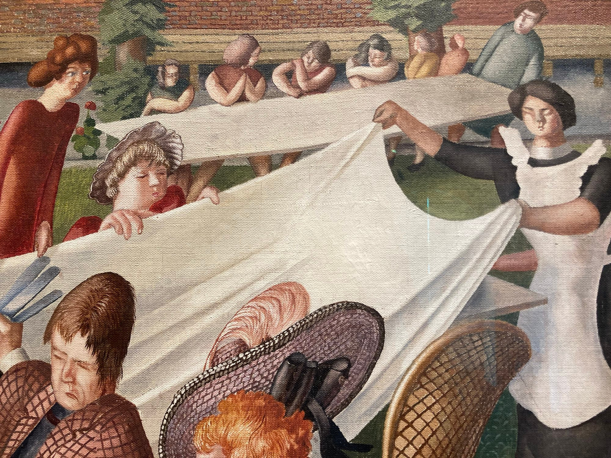 A maid is putting a tablecloth on another table just behind the main one. 