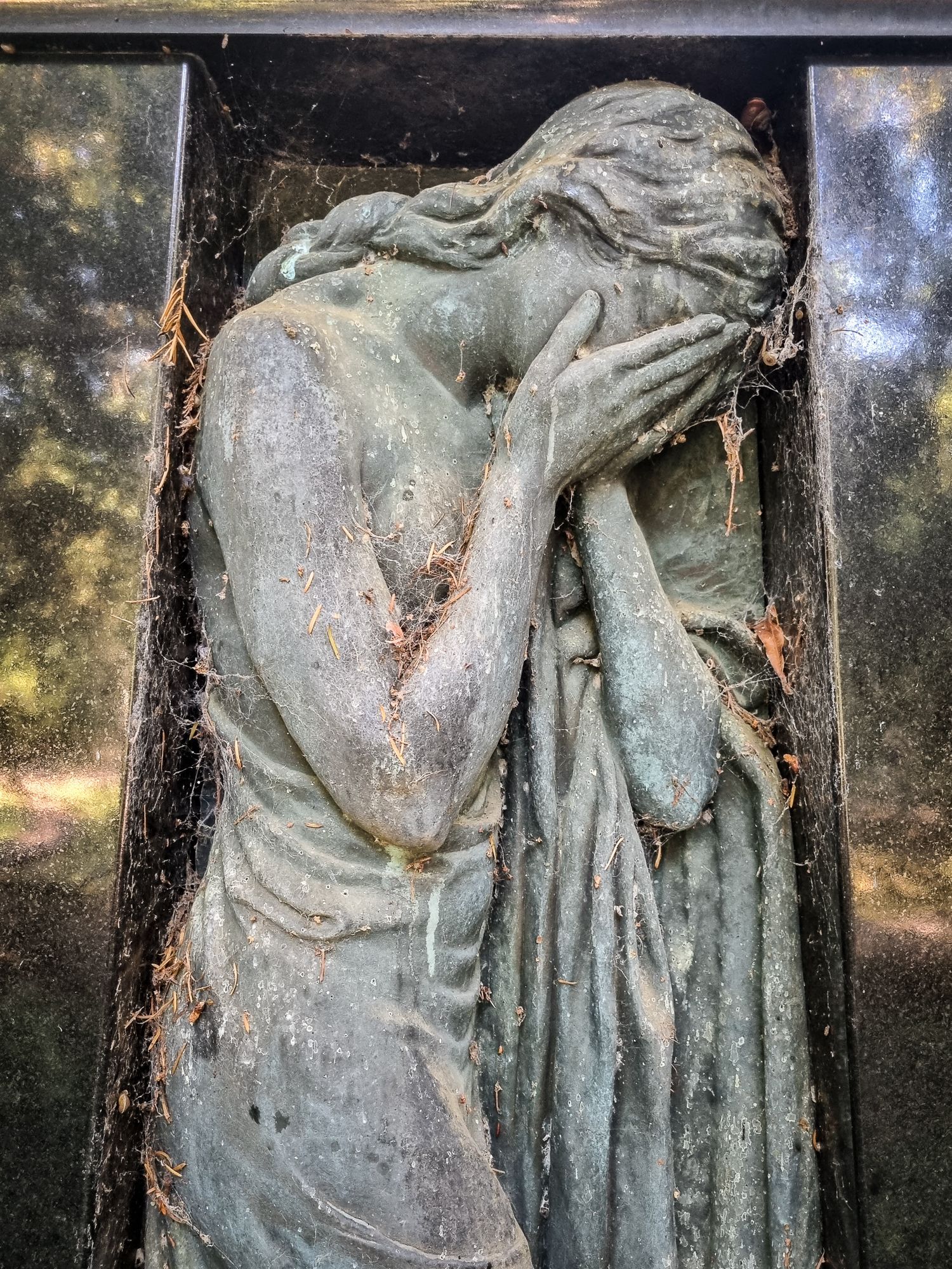 Gravestone depicting a woman in mourning, with her face in her hands.