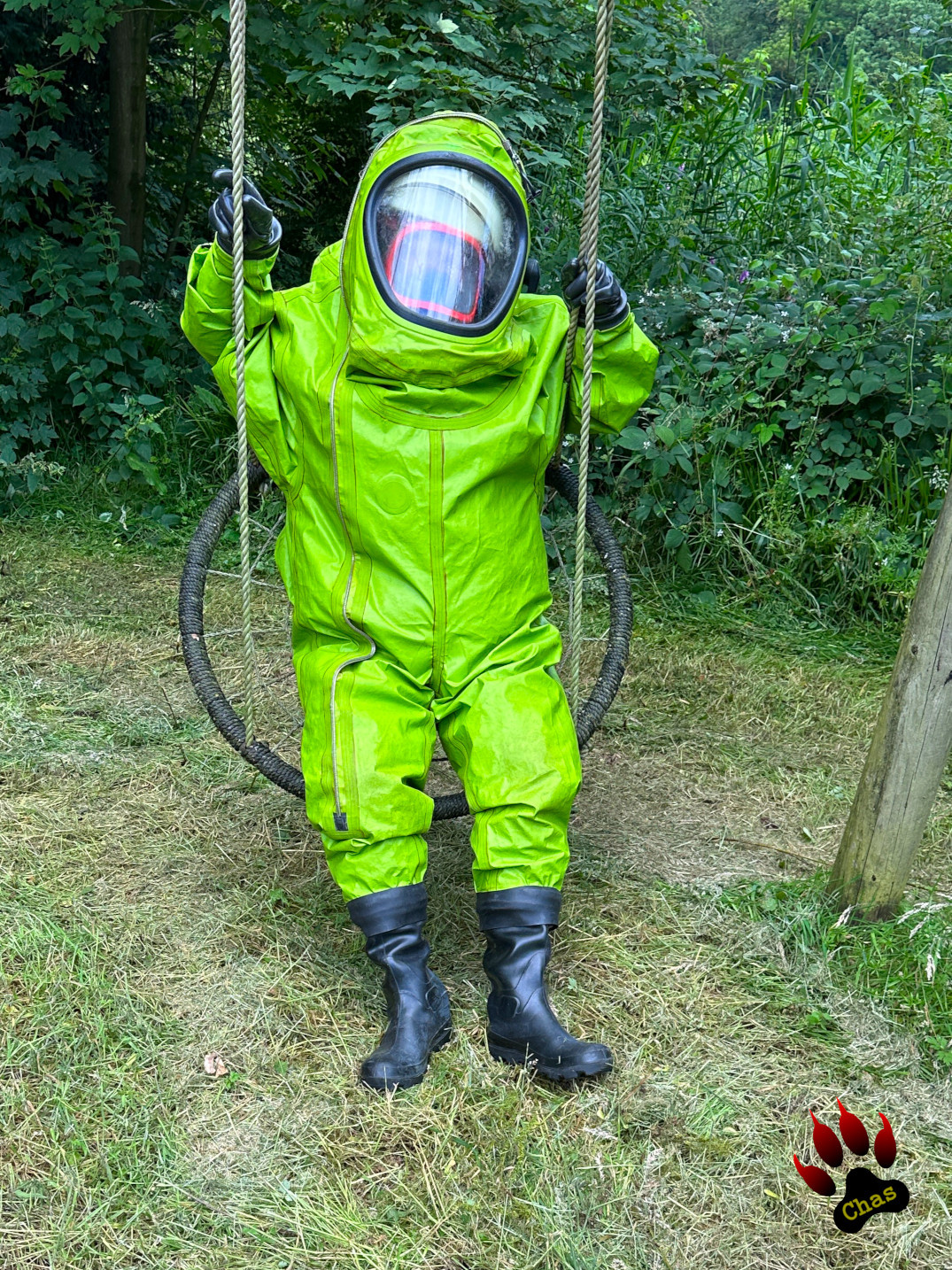 person in green hazmat suit with SCBA equipment sitting on a swing