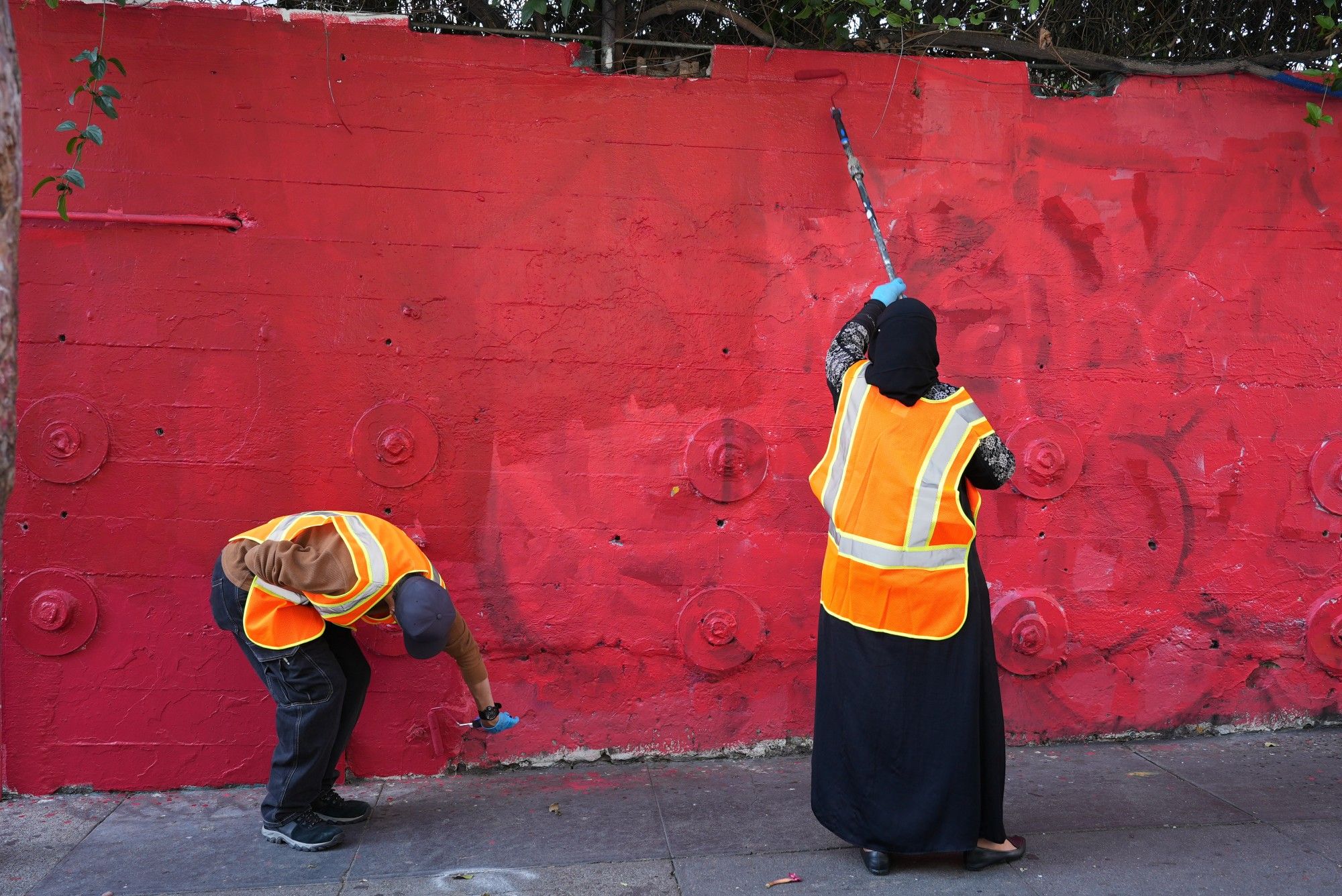 Two participants wipe out tags on a wall in the Tenderloin during a graffiti blitz on Friday, Oct. 4, 2024. Dozens of community volunteers and cleaning crews from Public Works and the Tenderloin Community Benefit District worked together to vanquish graffiti tags from public and private property in the Tenderloin.