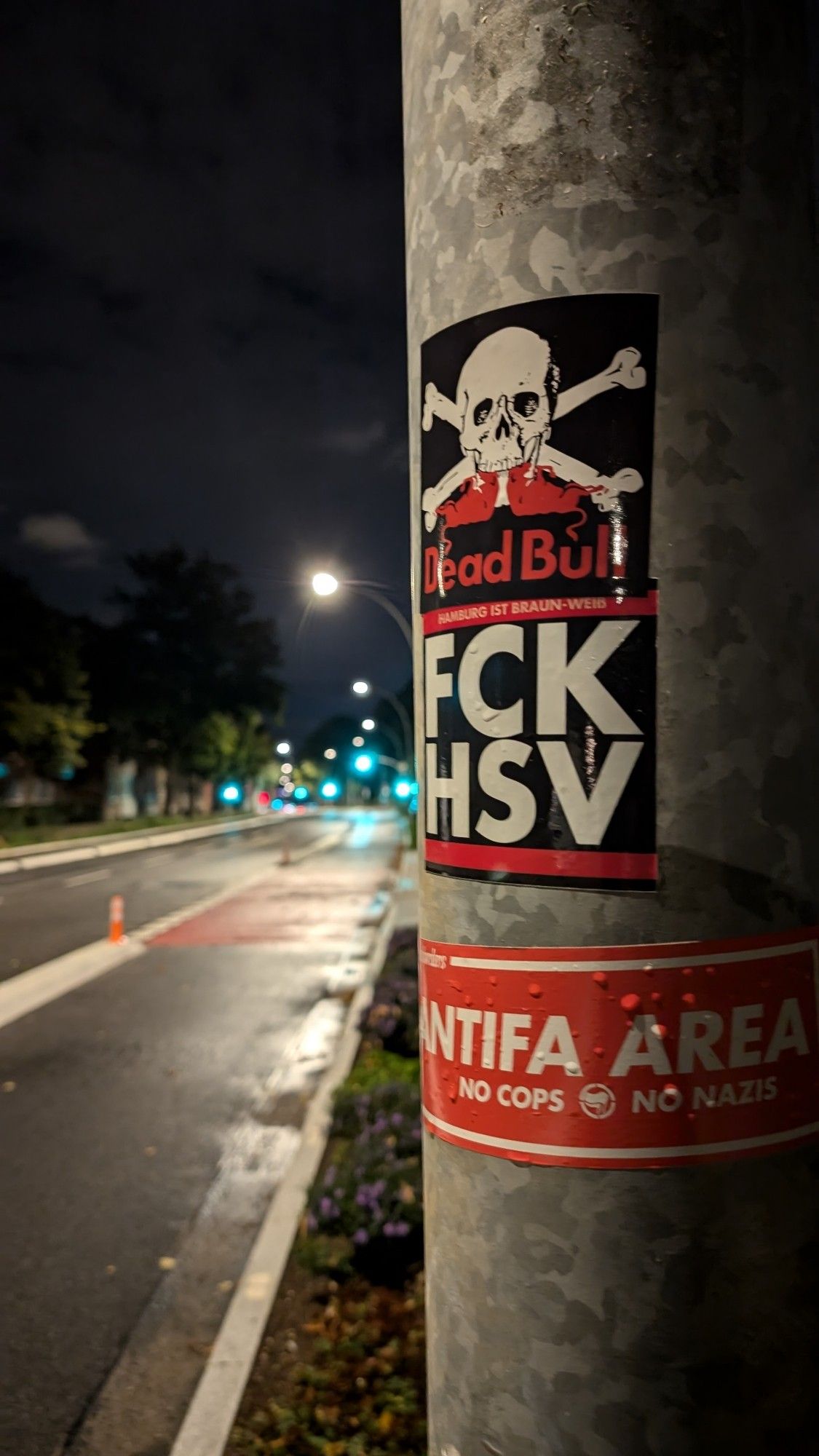 Drei Aufkleber an einer Laterne (von oben nach unten):
1. Der Dead Bull Aufkleber 
2. Ein FCKHSV Aufkleber 
3. Ein großer "Antifa Area" Aufkleber