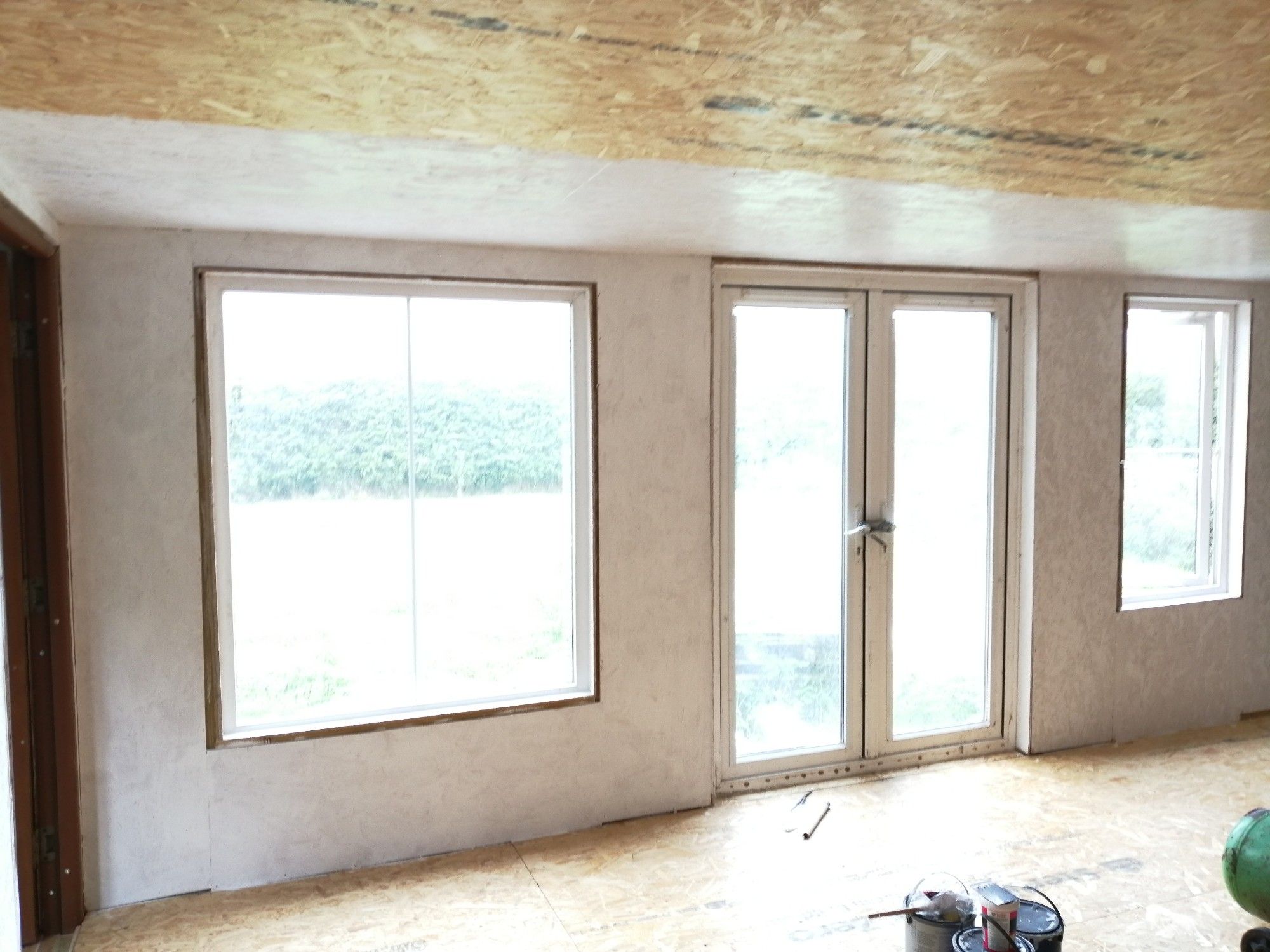 White painted wall of artstudio with 2 windows and a patio door.