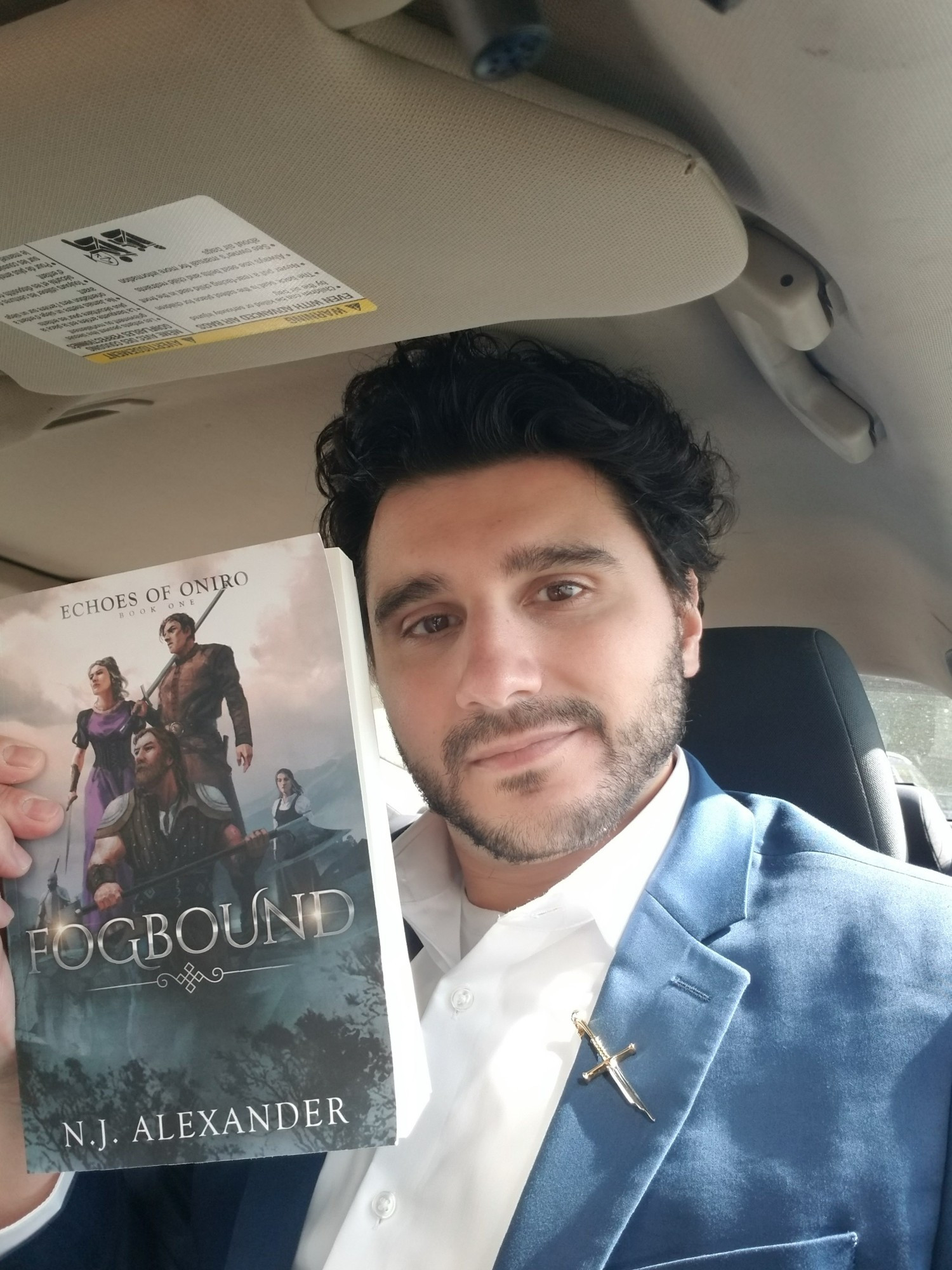 Author N.J. Alexander with a copy of his book, Fogbound. In a car, as he is wont to do.