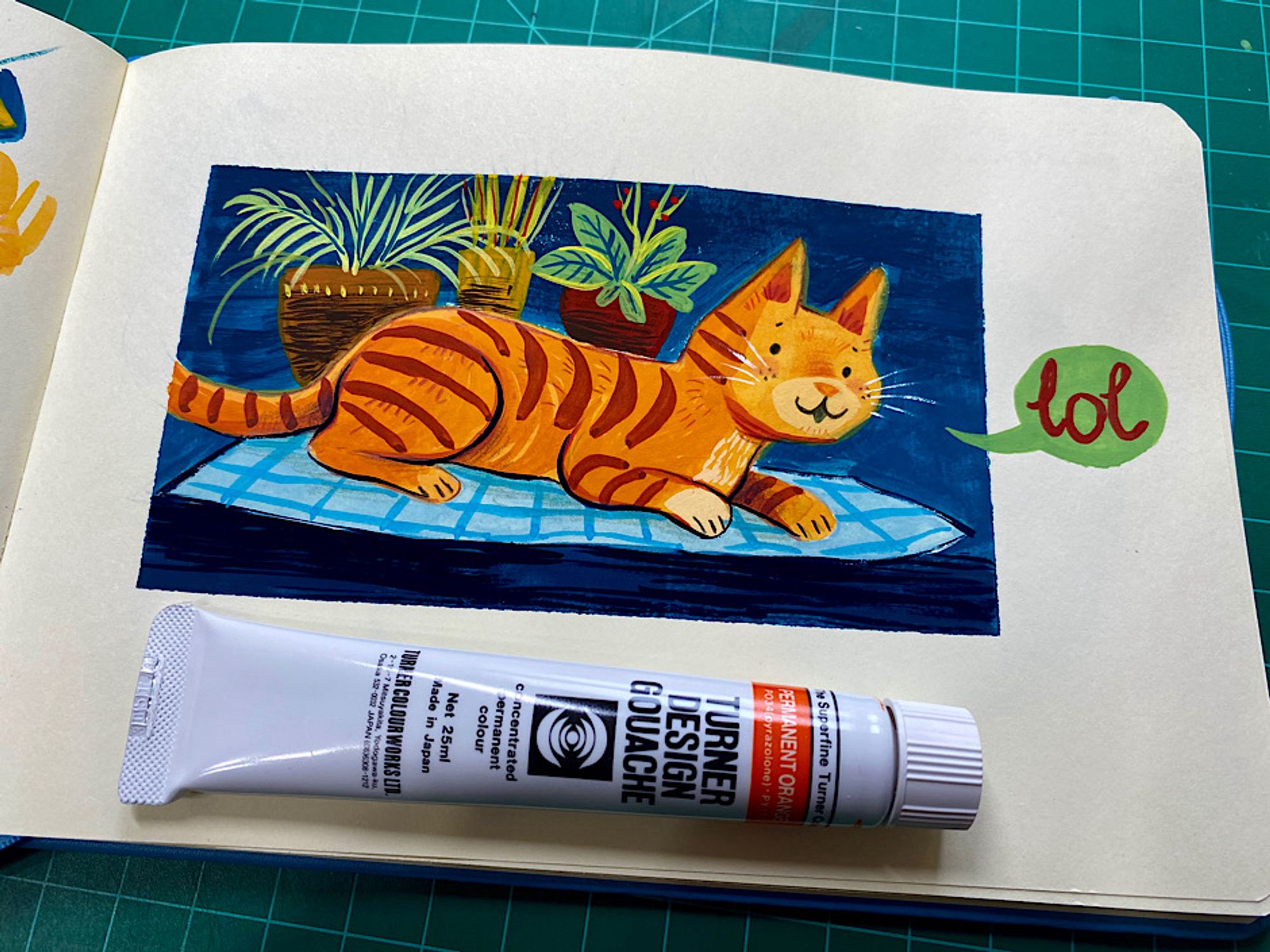 Gouache painting of an orange striped cat sitting on a blue blanket saying ‘lol’ in a green word balloon