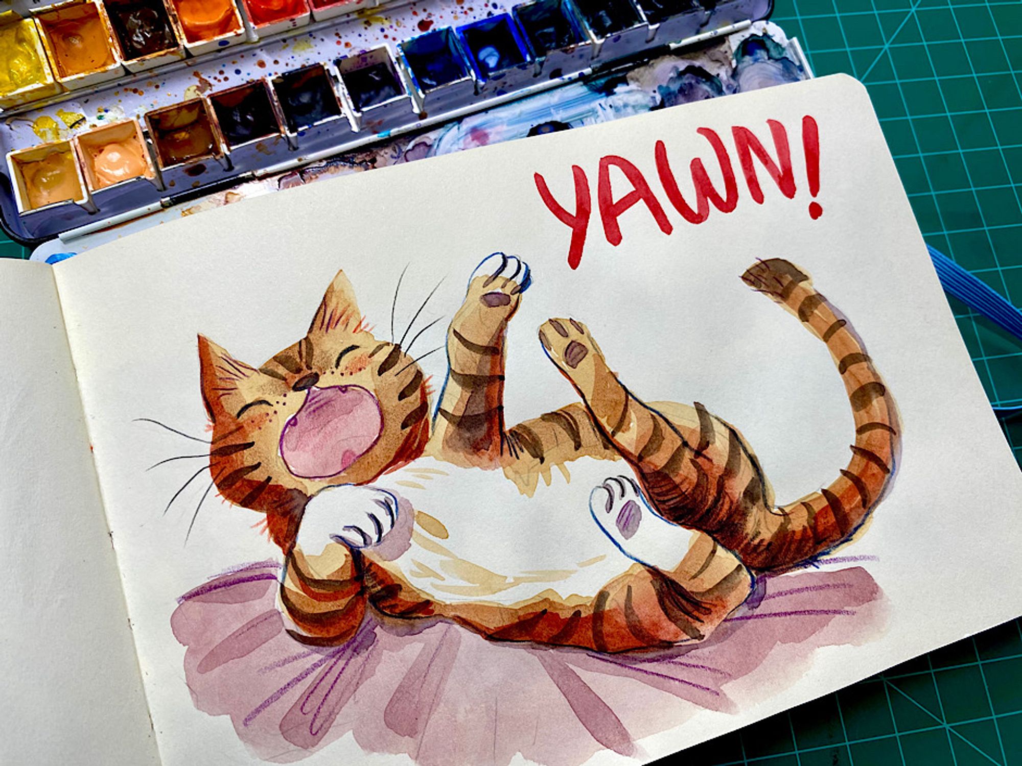 Striped orange cat rolling and having a big yawn