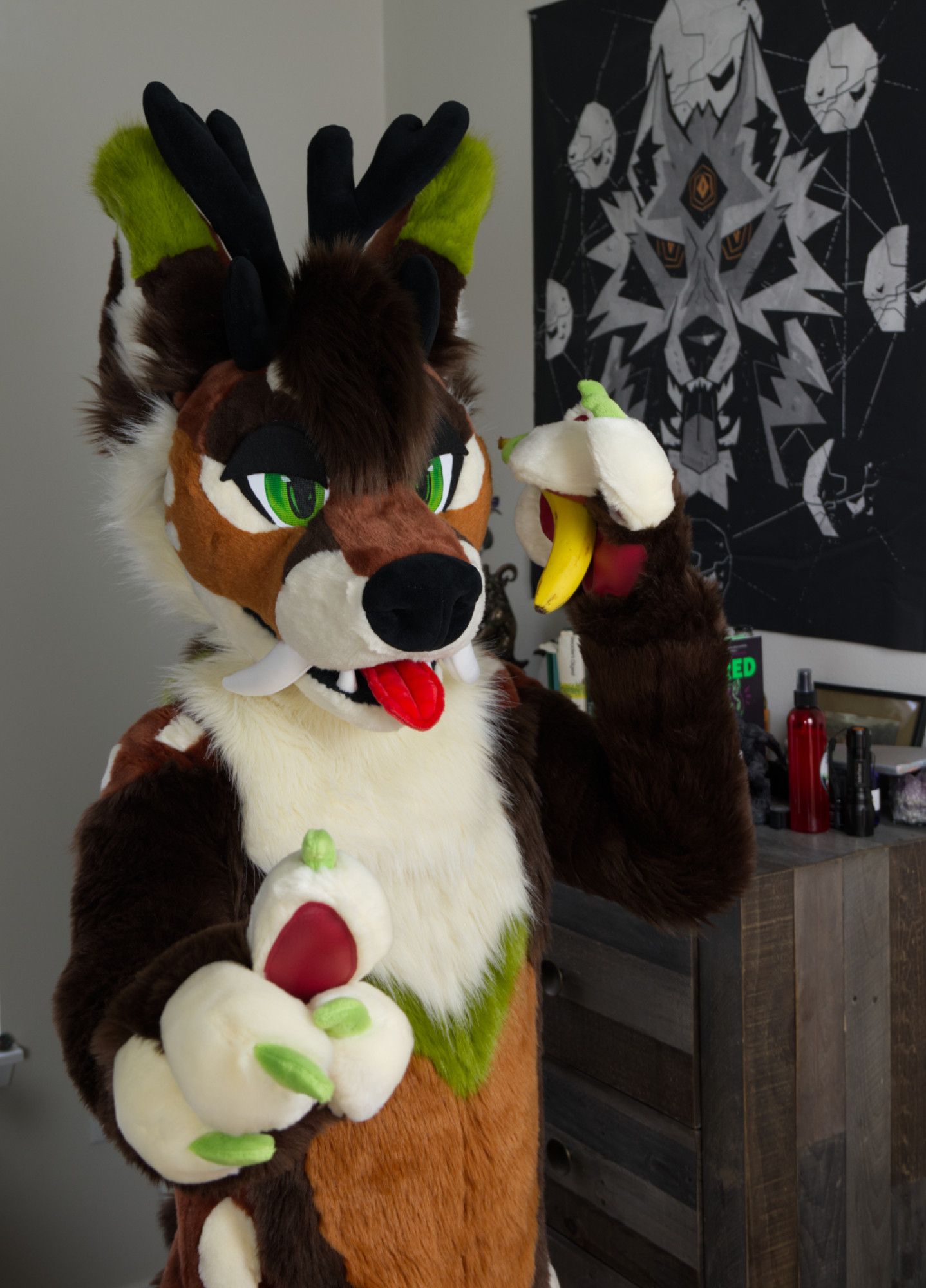 Larix, a brown, orange and green fox-deer fursuiter, motioning for you to hold while he chats on a B-A-N-A-N-N-A.