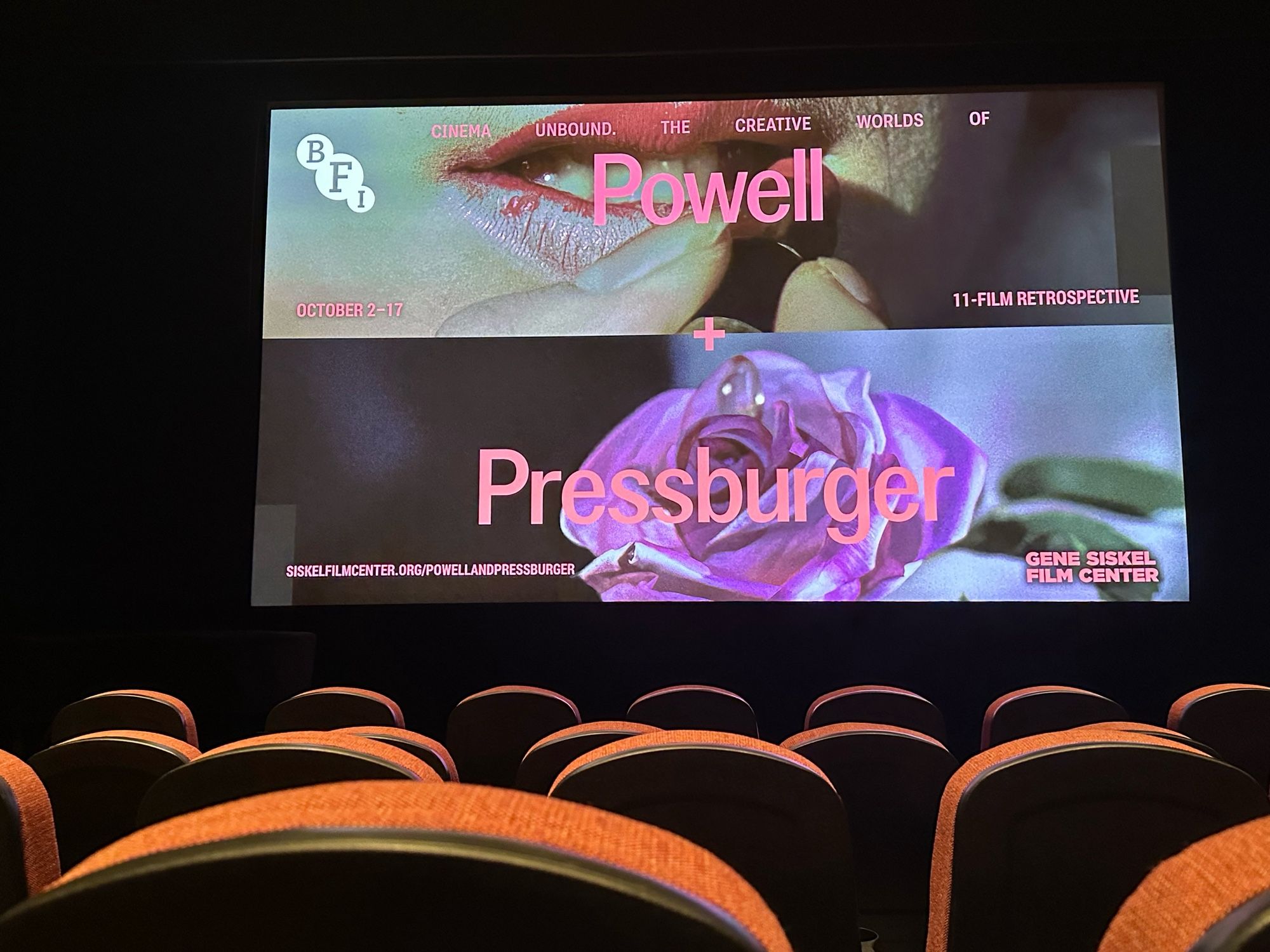 Movie theatre screen with a still image promoting Powell & Pressburger series. (Images are of a woman’s lips with lipstick being applied, and a lavender-colored rose).