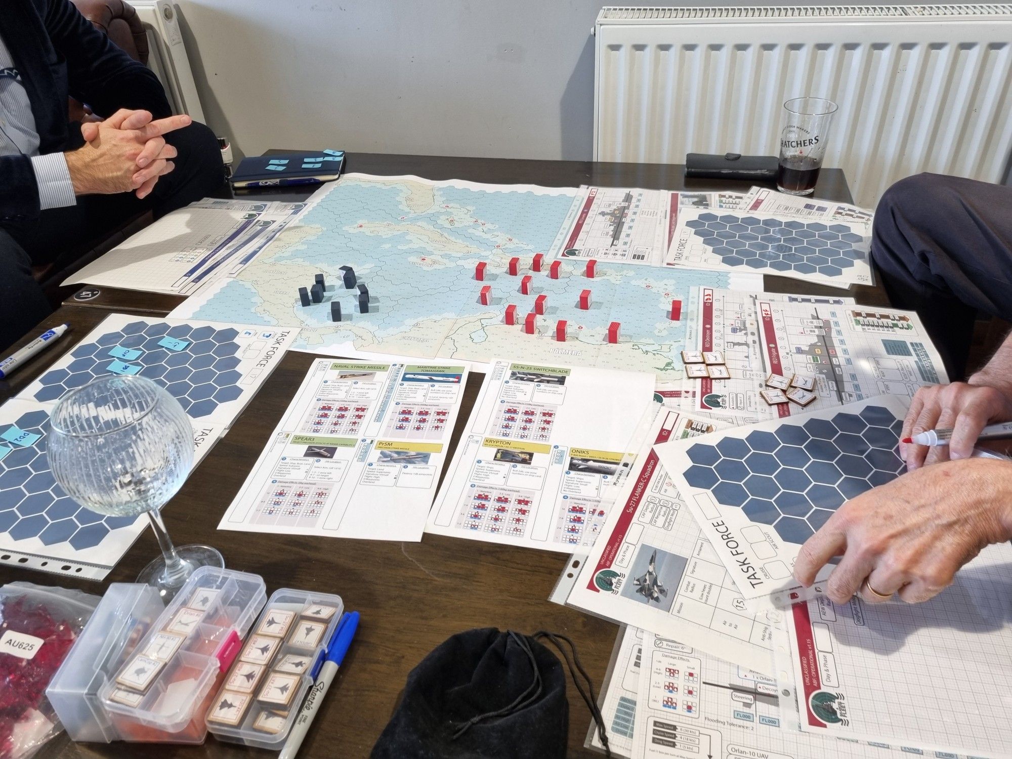 A pub table covered in maps and dozens of papers for a game of A Balanced Fleet.