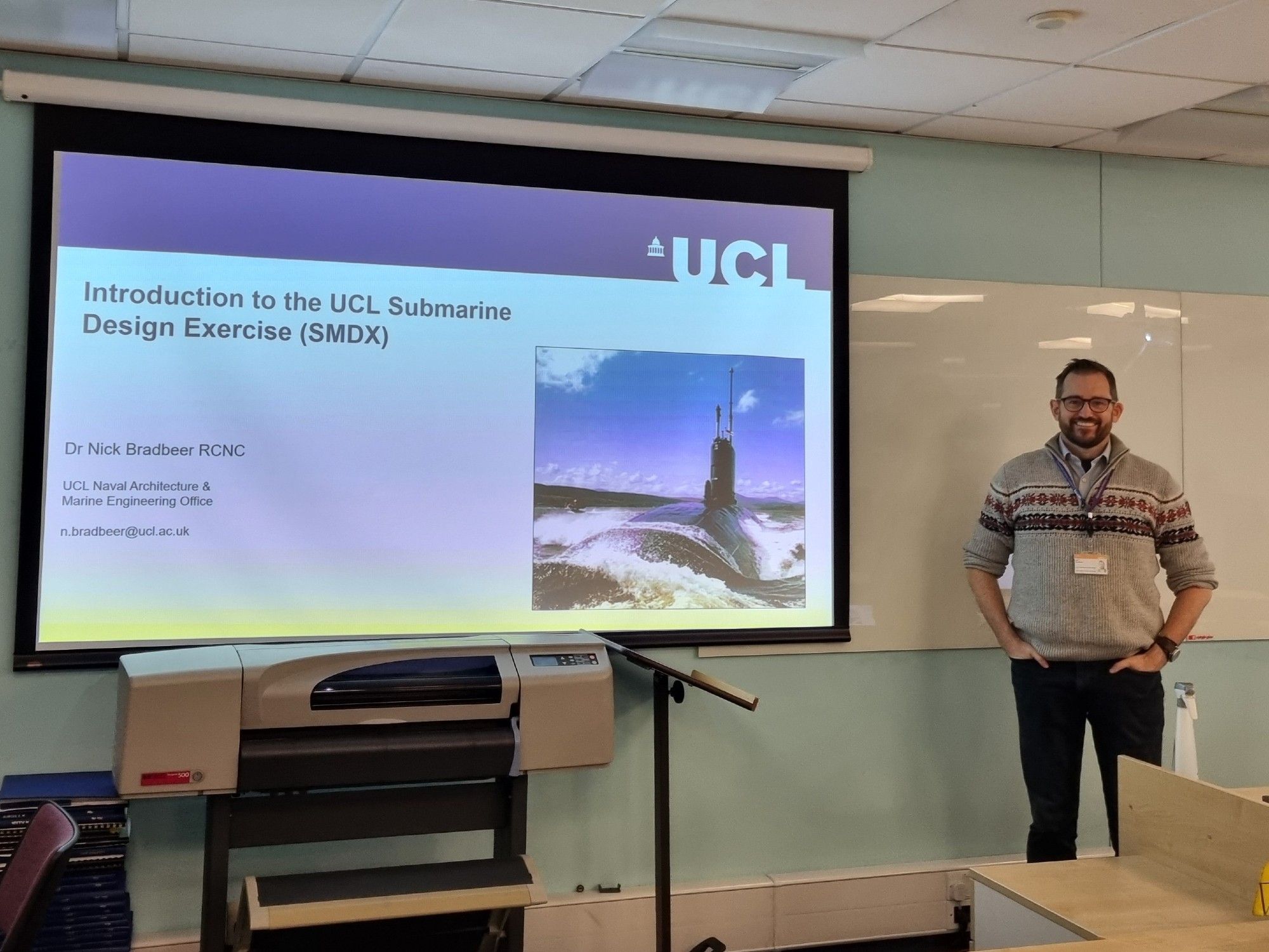 The author standing in front of a classroom projector screen, titled "Introduction to the UCL Submarine Design Exercise"