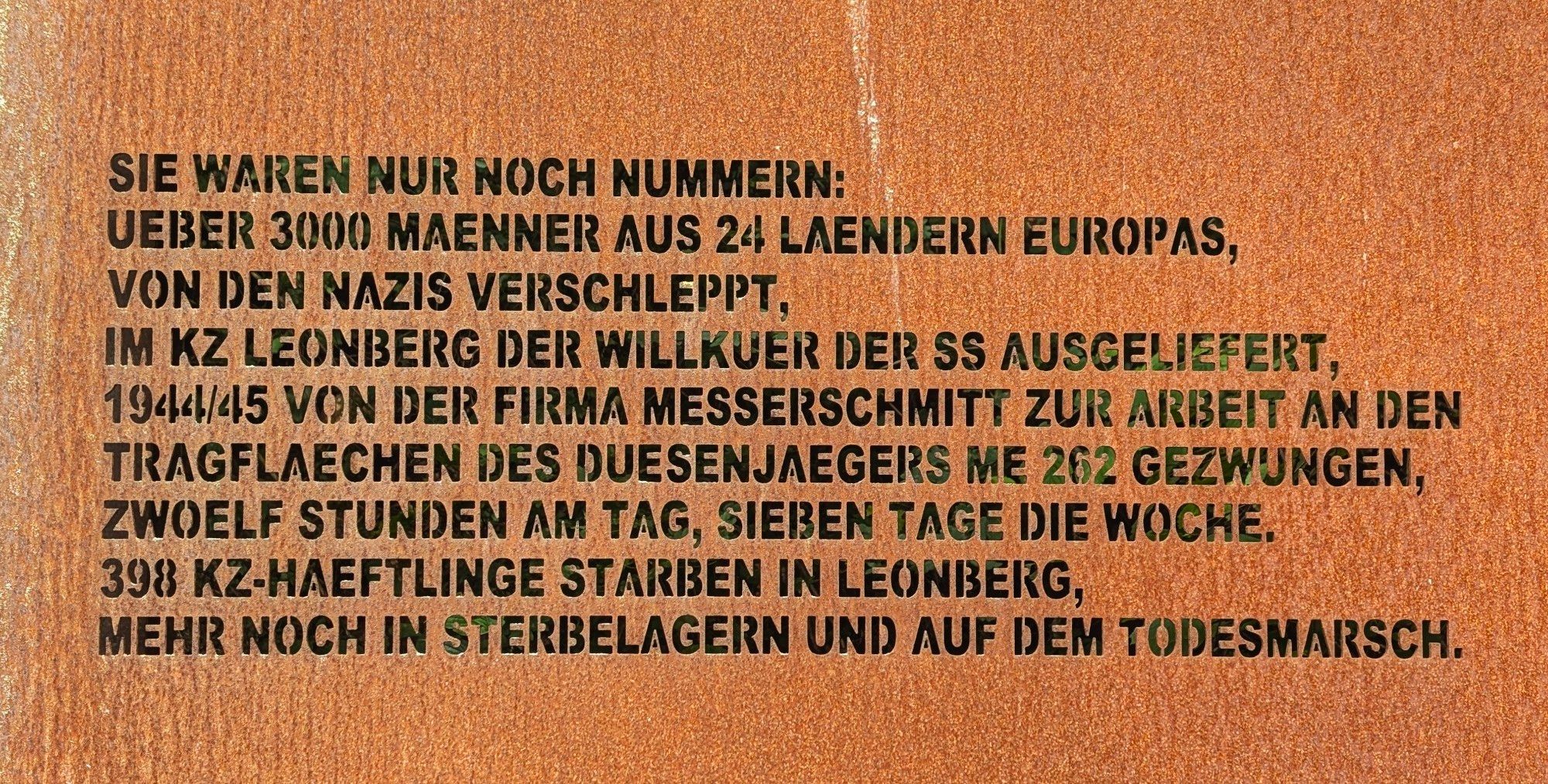 Eine rostige Stahlplatte in welche folgendes herausgelasert wurde :

SIE WAREN NUR NOCH NUMMERN:
UEBER 3000 MAENNER AUS 24 LAENDERN EUROPAS,
VON DEN NAZIS VERSCHLEPPT,
IM KZ LEONBERG DER WILLKUER DER SS AUSGELIEFERT,
1944/45 VON DER FIRMA MESSERSCHMITT ZUR ARBEIT AN DEN
TRAGFLAECHEN DES DUESENJAEGERS ME 262 GEZWUNGEN,
ZWOELF STUNDEN AM TAG, SIEBEN TAGE DIE WOCHE.
398 KZ-HAEFTLINGE STARBEN IN LEONBERG,
MEHR NOCH IN STERBELAGERN UND AUF DEM TODESMARSCH.