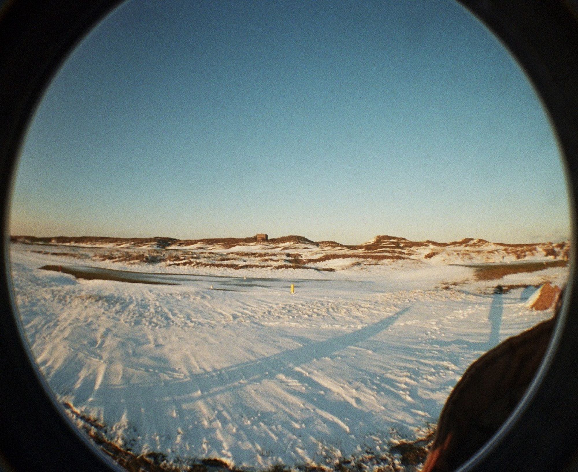 A beach at sunset, covered in snow, with long shadows