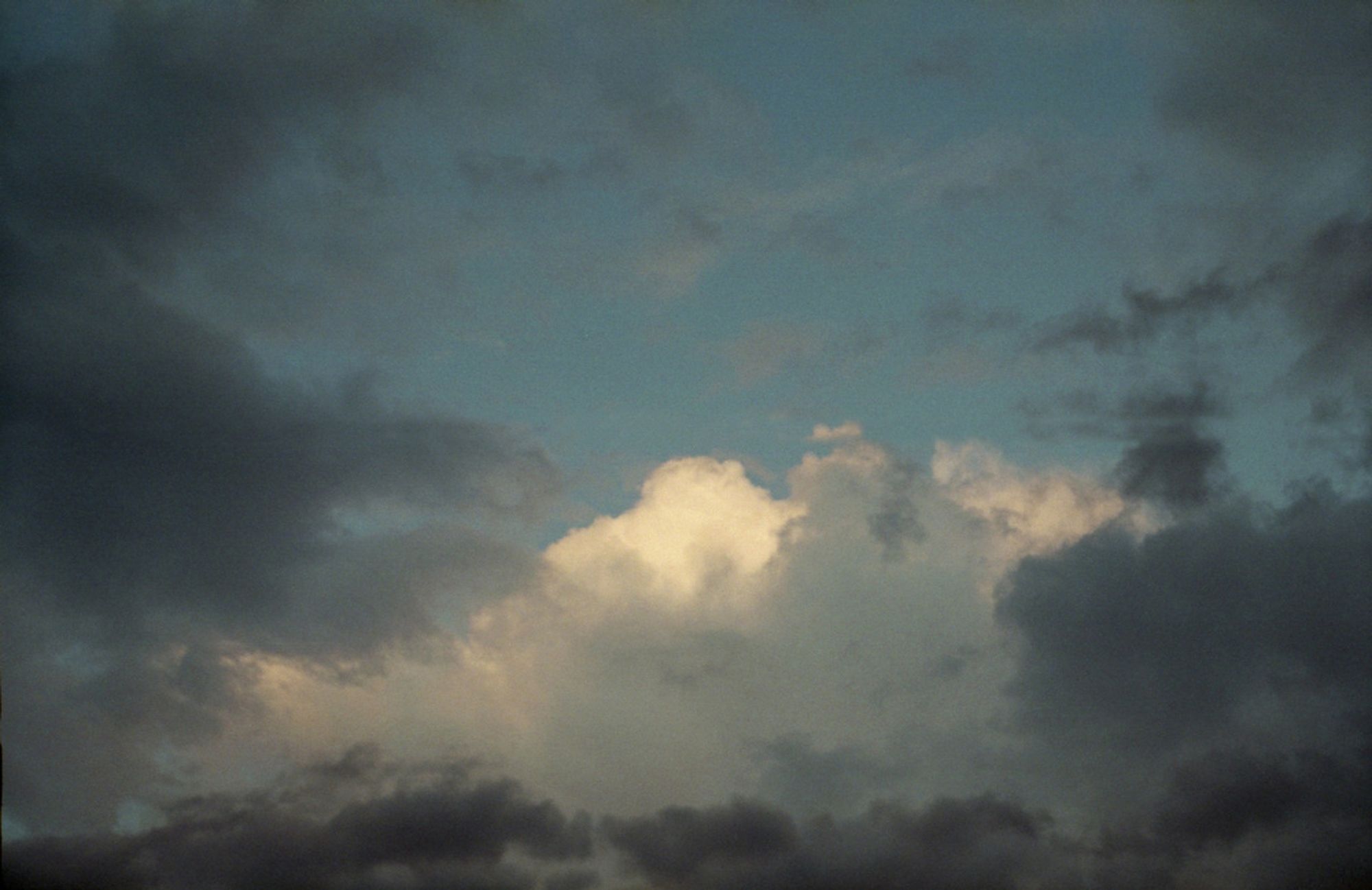 a photo of a white cloud in a blue sky, with darker clouds surrounding it. It looks more like a painting than a photograph