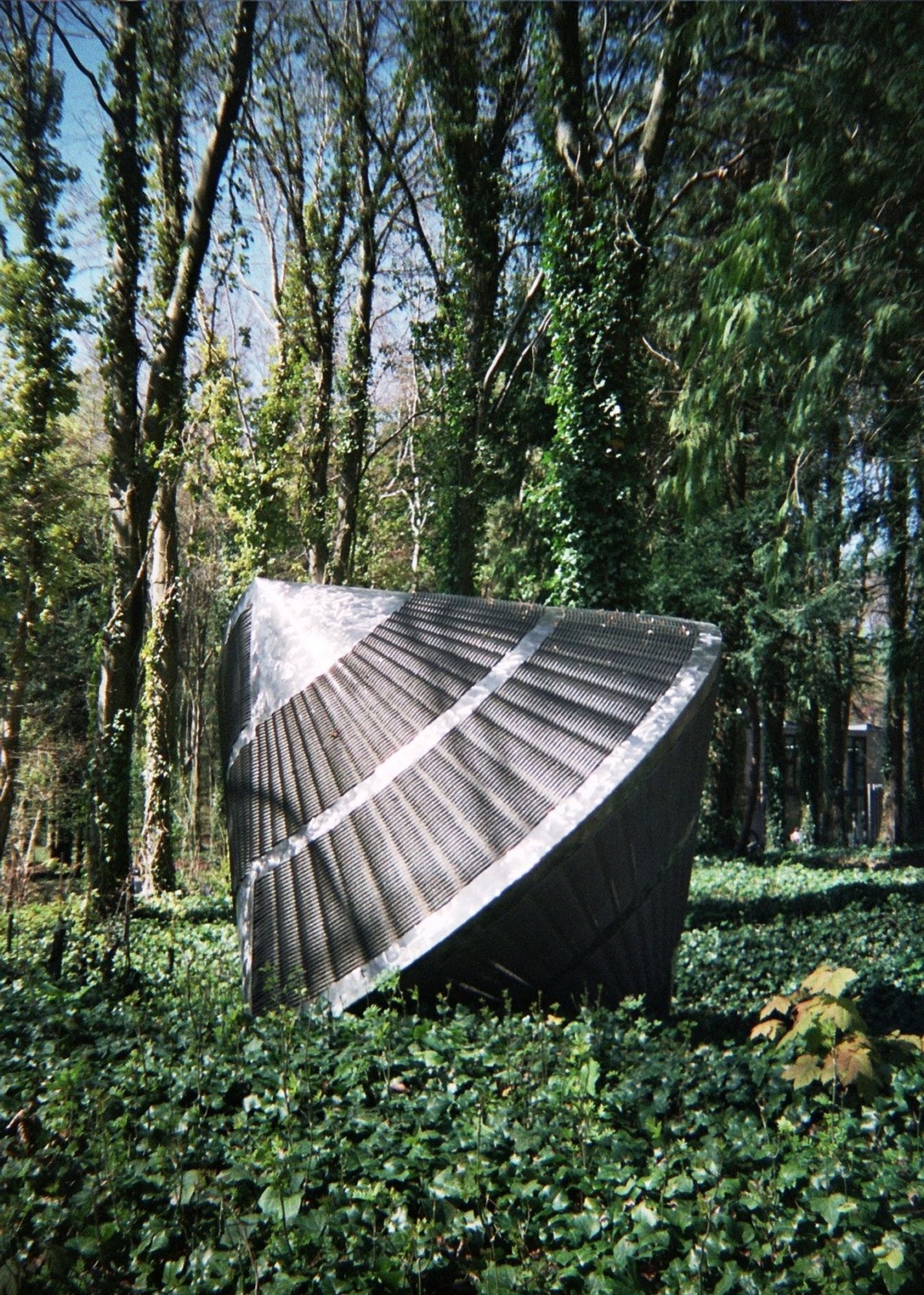 a sculpture that looks like some sort of space capsule sat in the woods in the sunlight