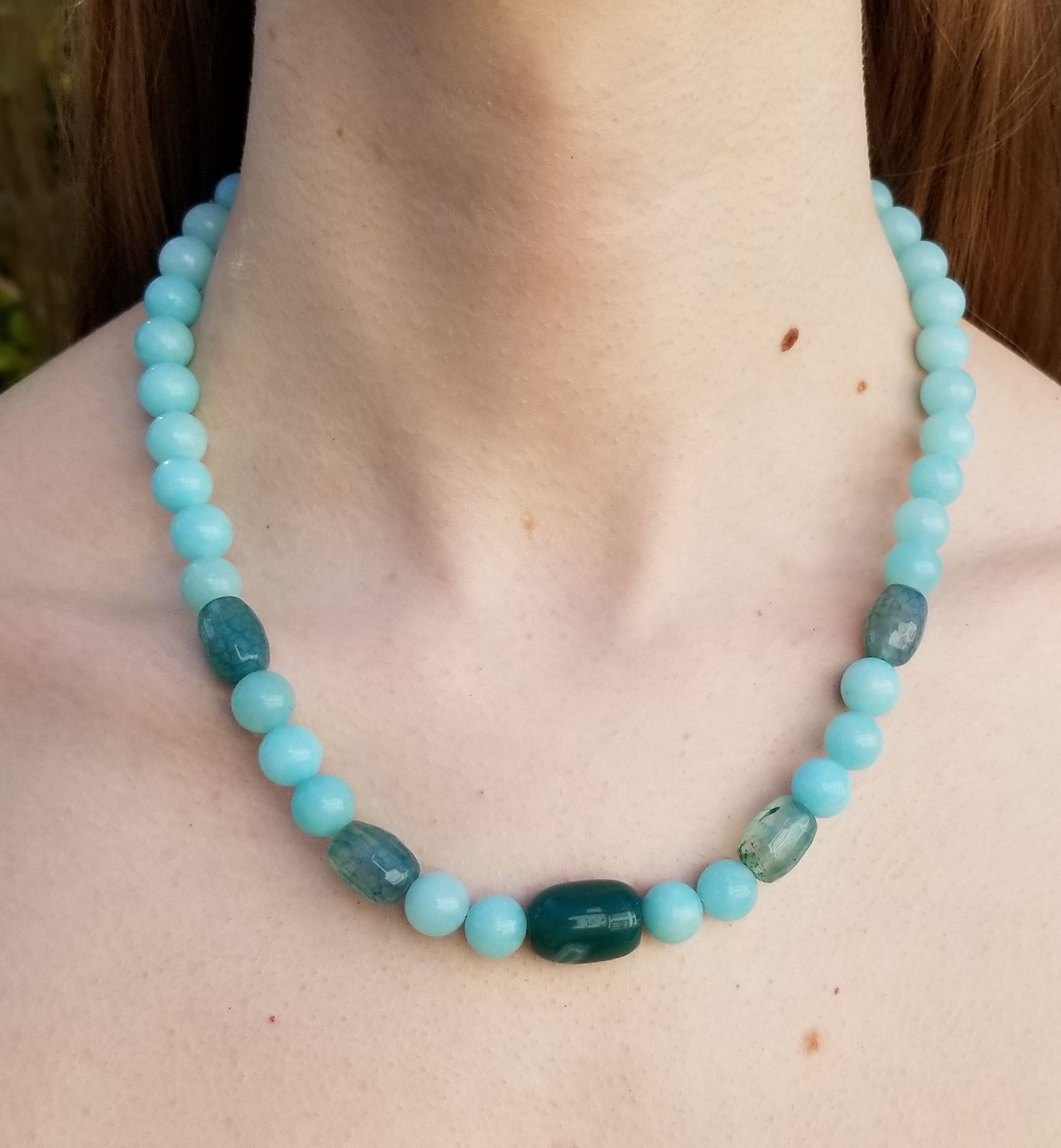 Necklace of aquamarine and jade, about collar bone length, on a model