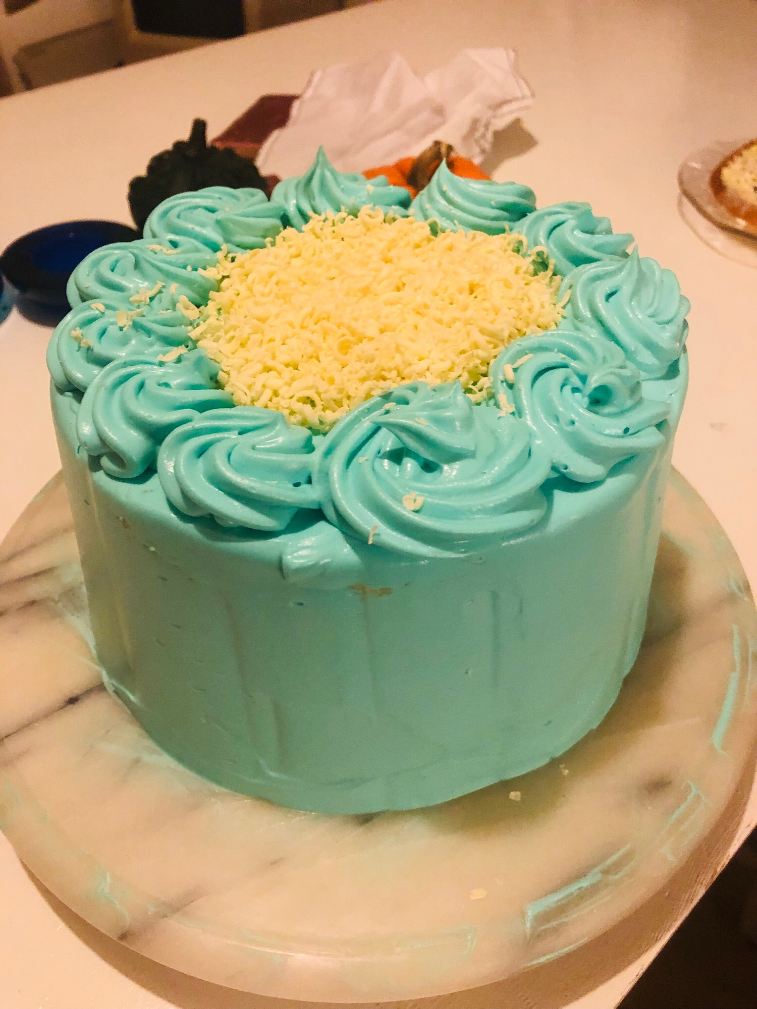 a cake covered in white chocolate mousse dyed blue, and topped with shavings of white chocolate