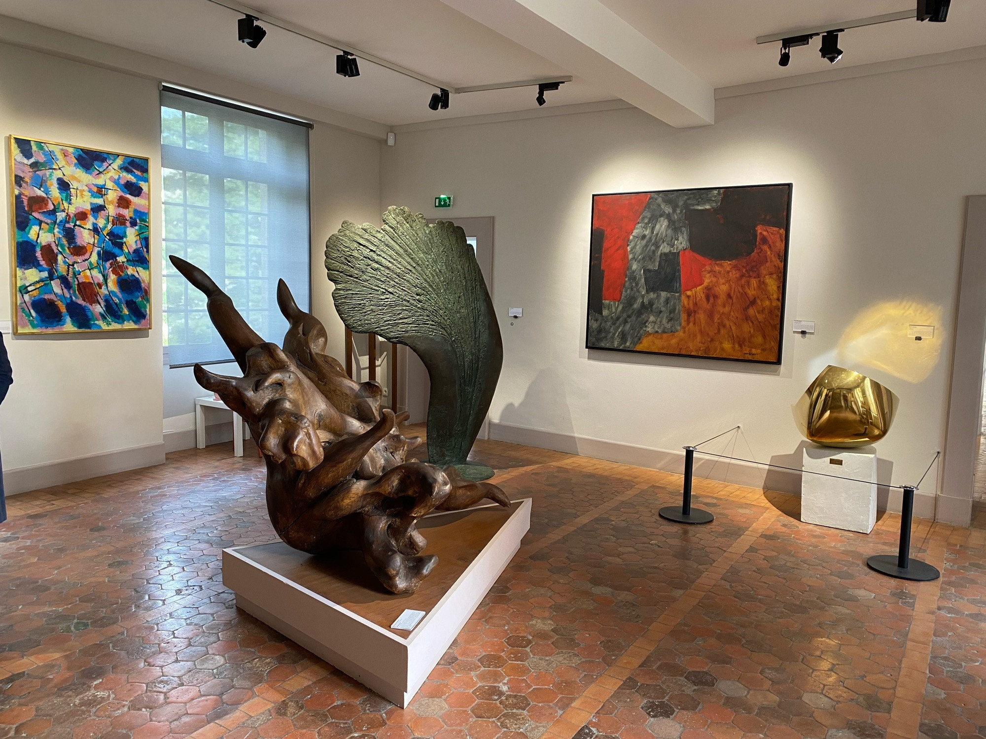 Photo d’une salle de musée avec des sculptures modernes et des tableaux abstraits au mur.