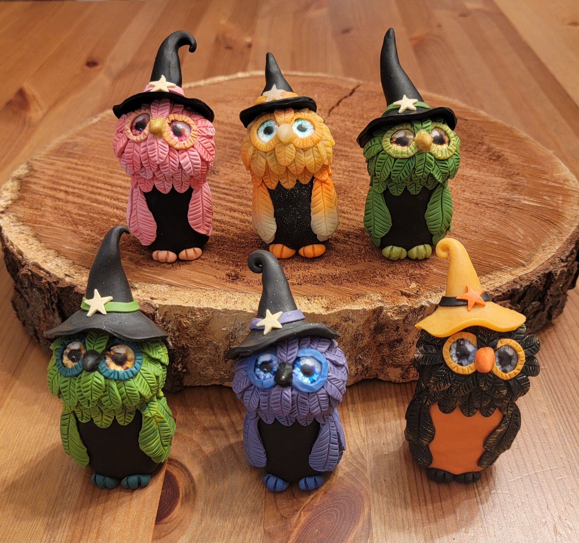 Six polymer clay owls in witch hats, standing on two levels