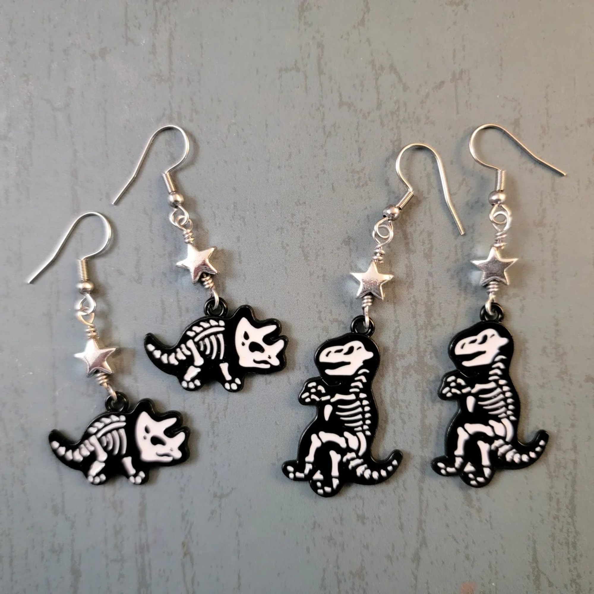 Two pairs of dinosaur skeleton earrings with stars