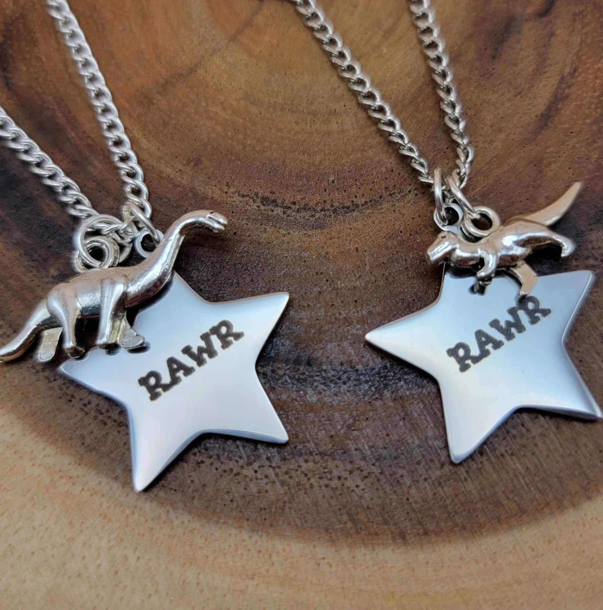 Two dinosaur necklaces, each with a dino charm and a star that says RAWR