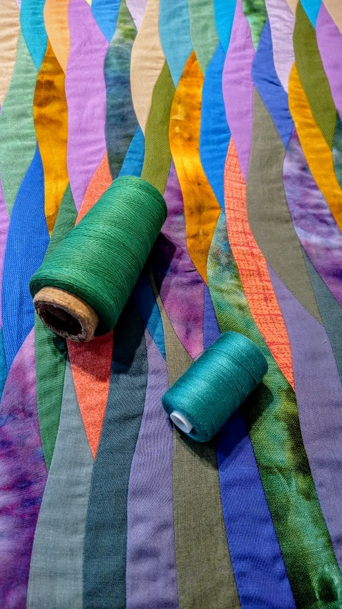 spools of thread lying on a quilt