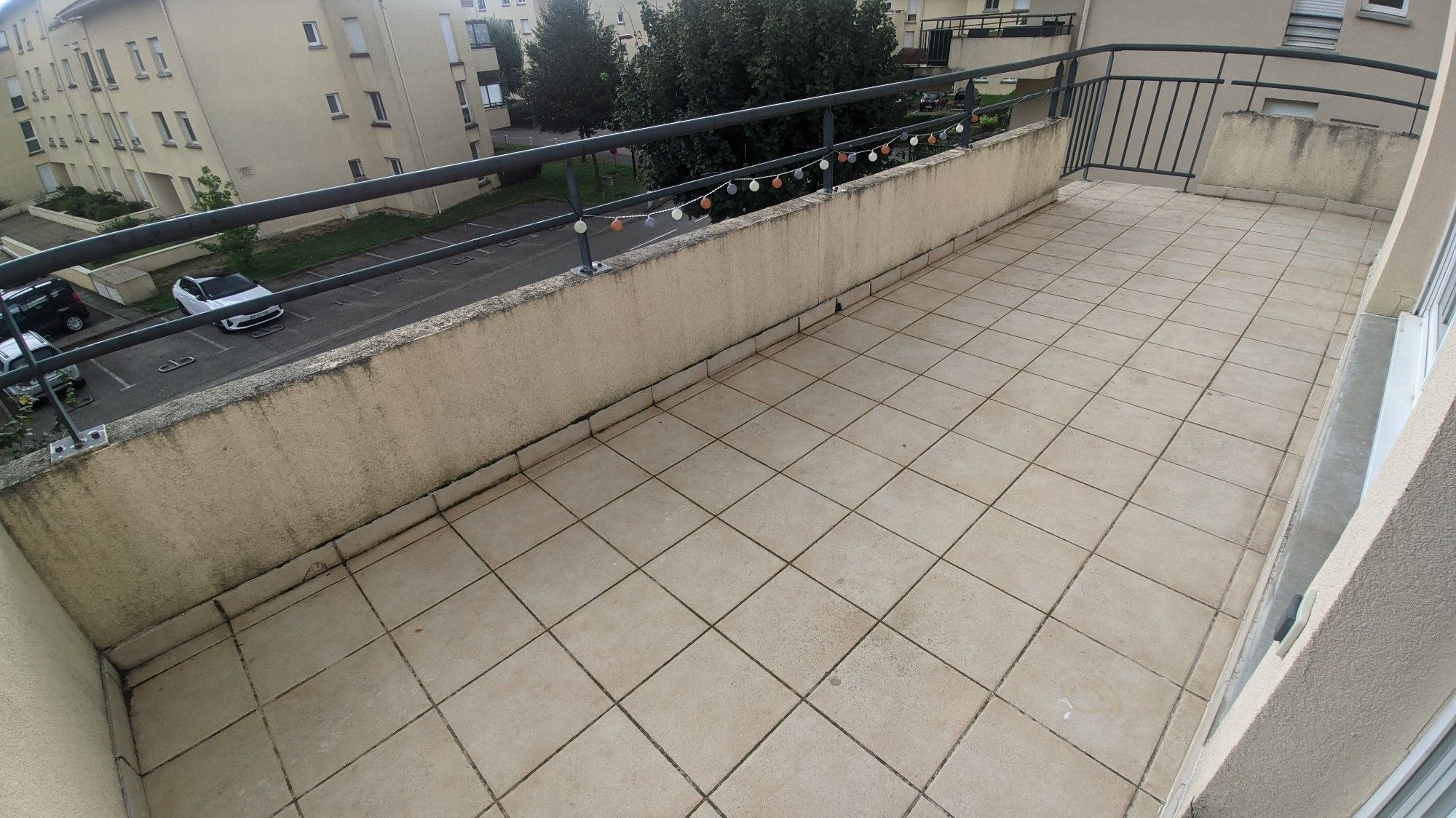 Photo d'une terrasse vide avec une petite guirlande électrique accrochée à la barrière.