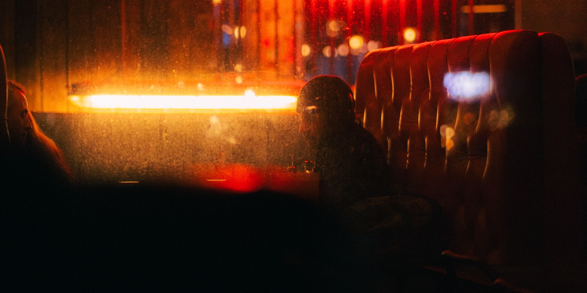 Outside capture of two men sitting at a bar, lights reflecting on glass