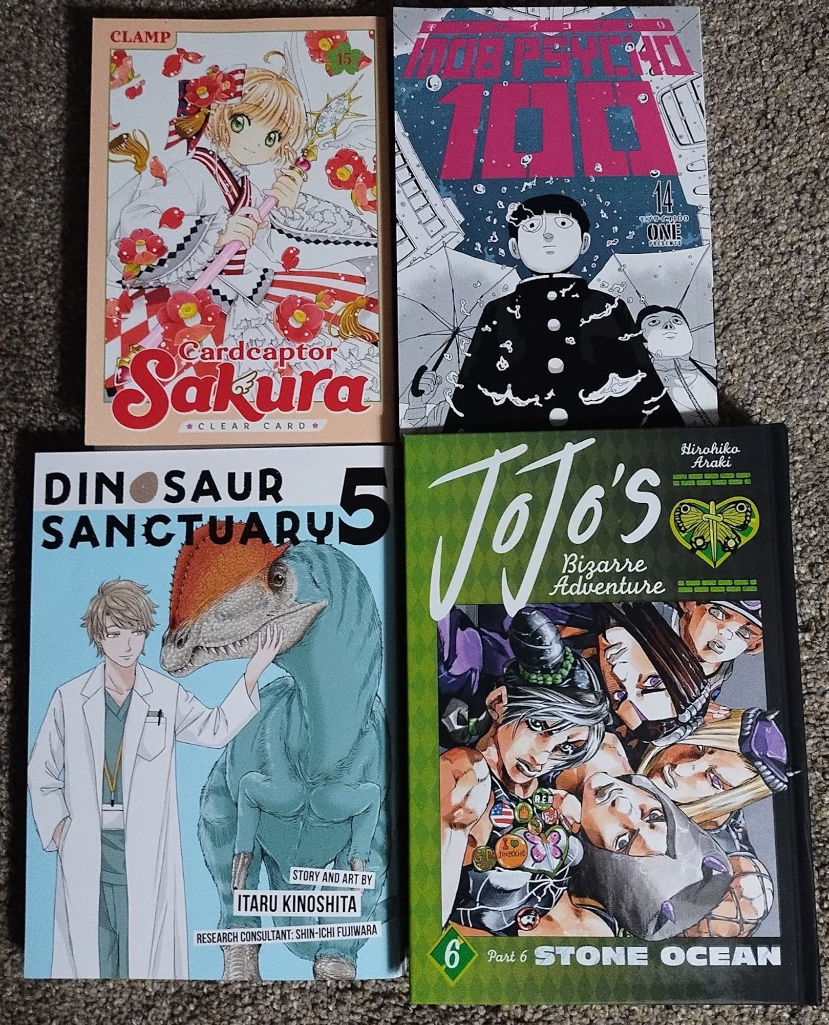 An image of the front covers of Volume 15 of the Cardcaptor Sakura: Clear Card manga, Volume 14 of the Mob Psycho 100 Manga, Volume 5 of the Dinosaur Sanctuary manga, and Volume 6 of the Jojo's Bizarre Adventure Part 6 Stone Ocean manga.