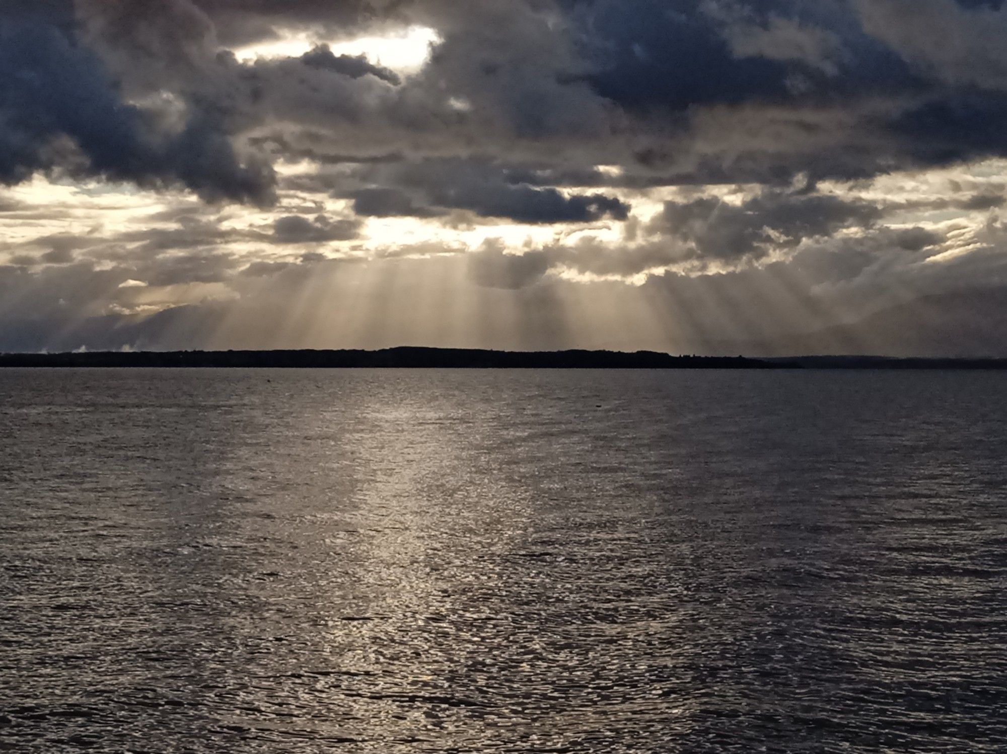 Rayon de soleil après la pluie le lac au fond le Jura et un ciel chargé.