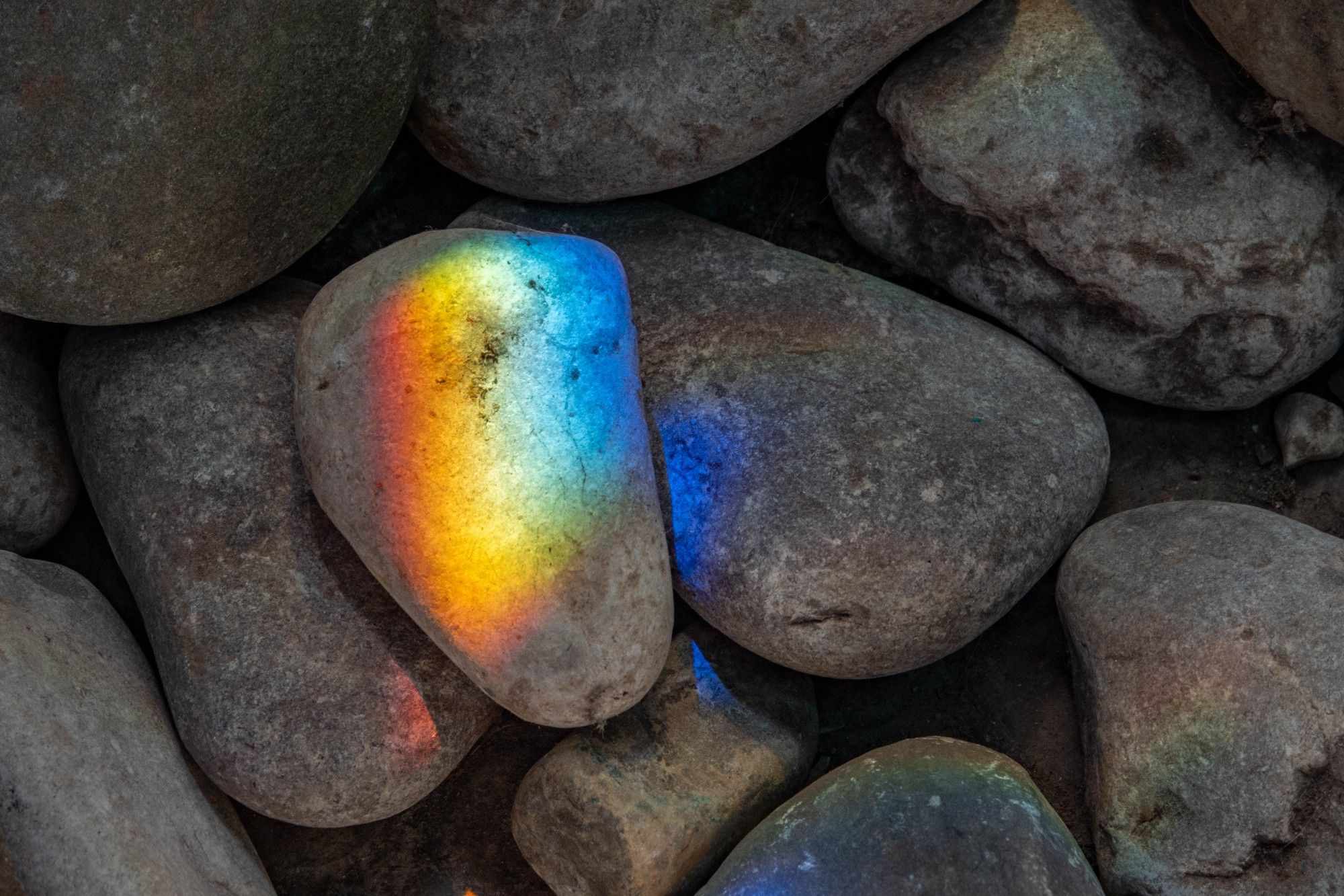 Large grey stones, with one illuminated by a spectrum of coloured light.