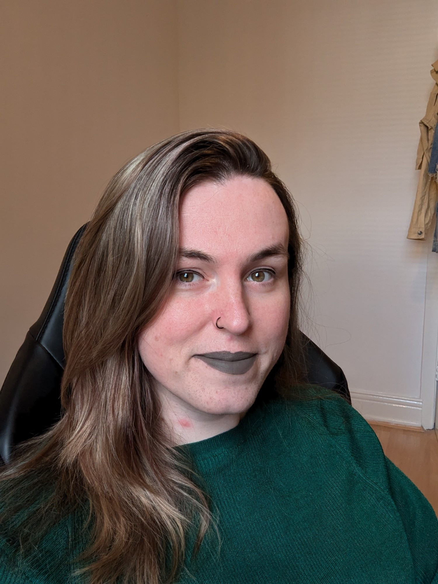 A picture of Aoife. She is wearing a green top, and wearing dark grey lipstick 