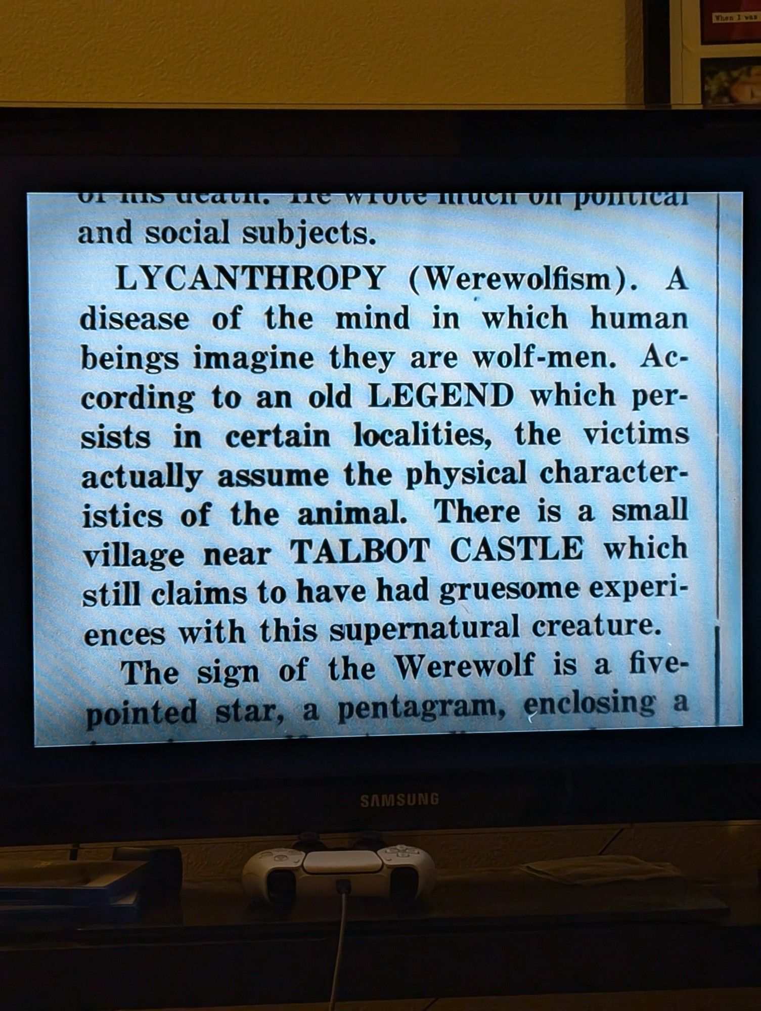 A photo of a TV screen with text. The text reads "Lycanthropy (Werewolfism). A disease of the mind in which beings imagine they are wolf-men. According to an old legend which persists in certain localities, the victims actually assume the physical characteristics of the animal. There is a small village near Talbot Castle which still claims yo have had gruesome experiences with this supernatural creature."