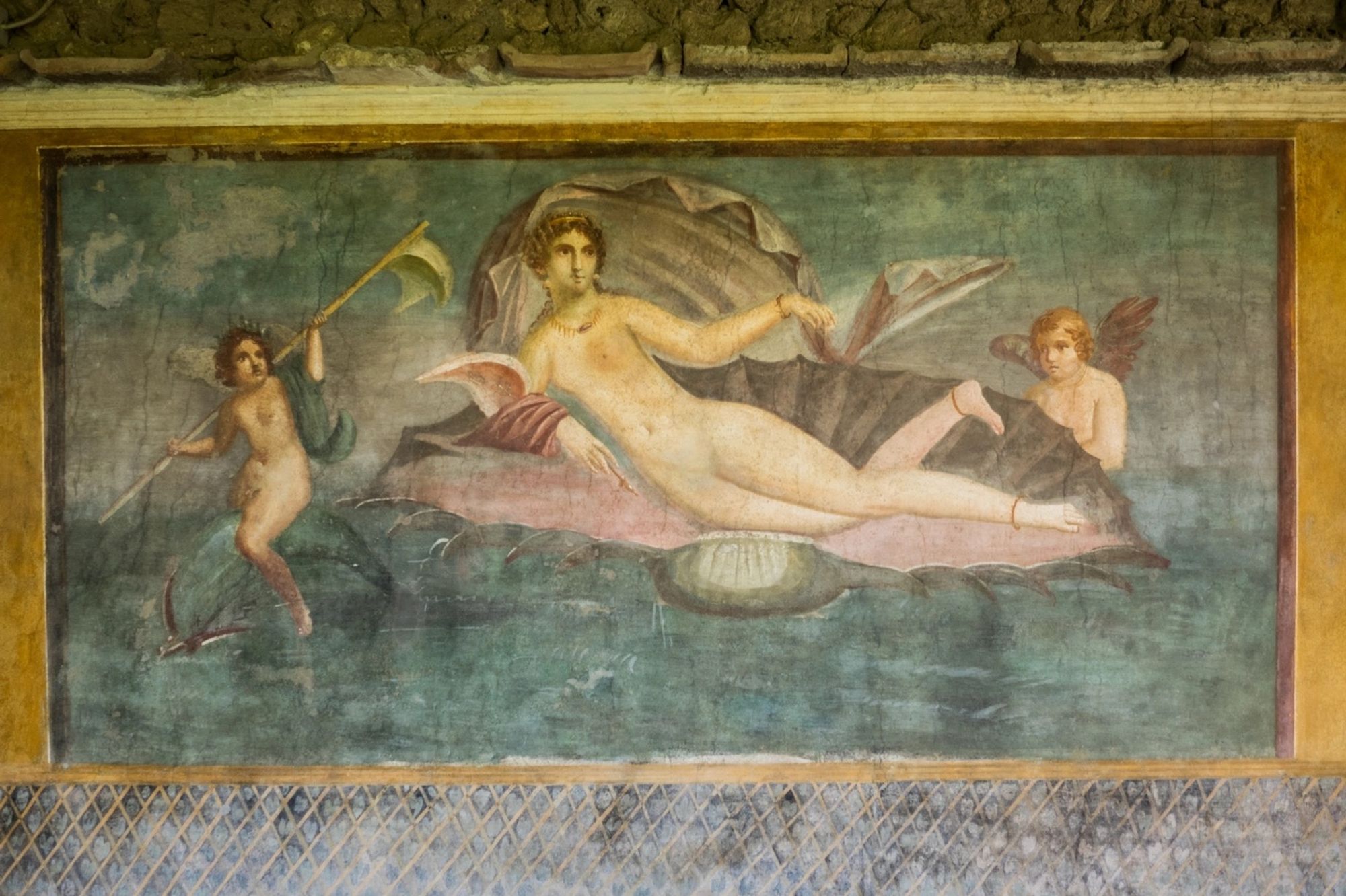 Fresco known as ‘The Birth of Venus’ from House of Venus in the Shell at Pompeii. She is reclining almost nude except for a strategic fabric drape over one arm and some jewellery (anklets and a necklace). She is accompanied by some erotes, one riding a dolphin and the other watching one, perhaps Cupid himself.