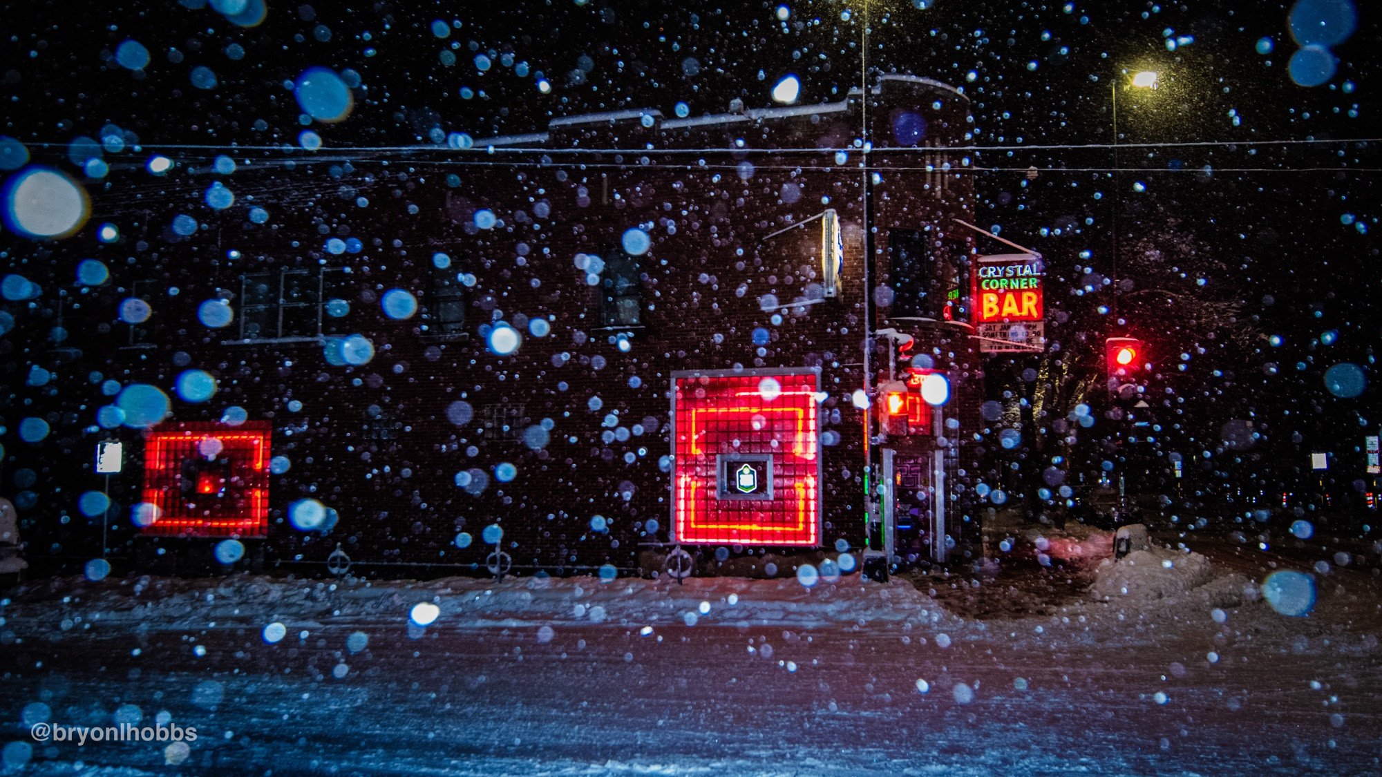 Image of a bar lit up by its neon lights in a snow storm 