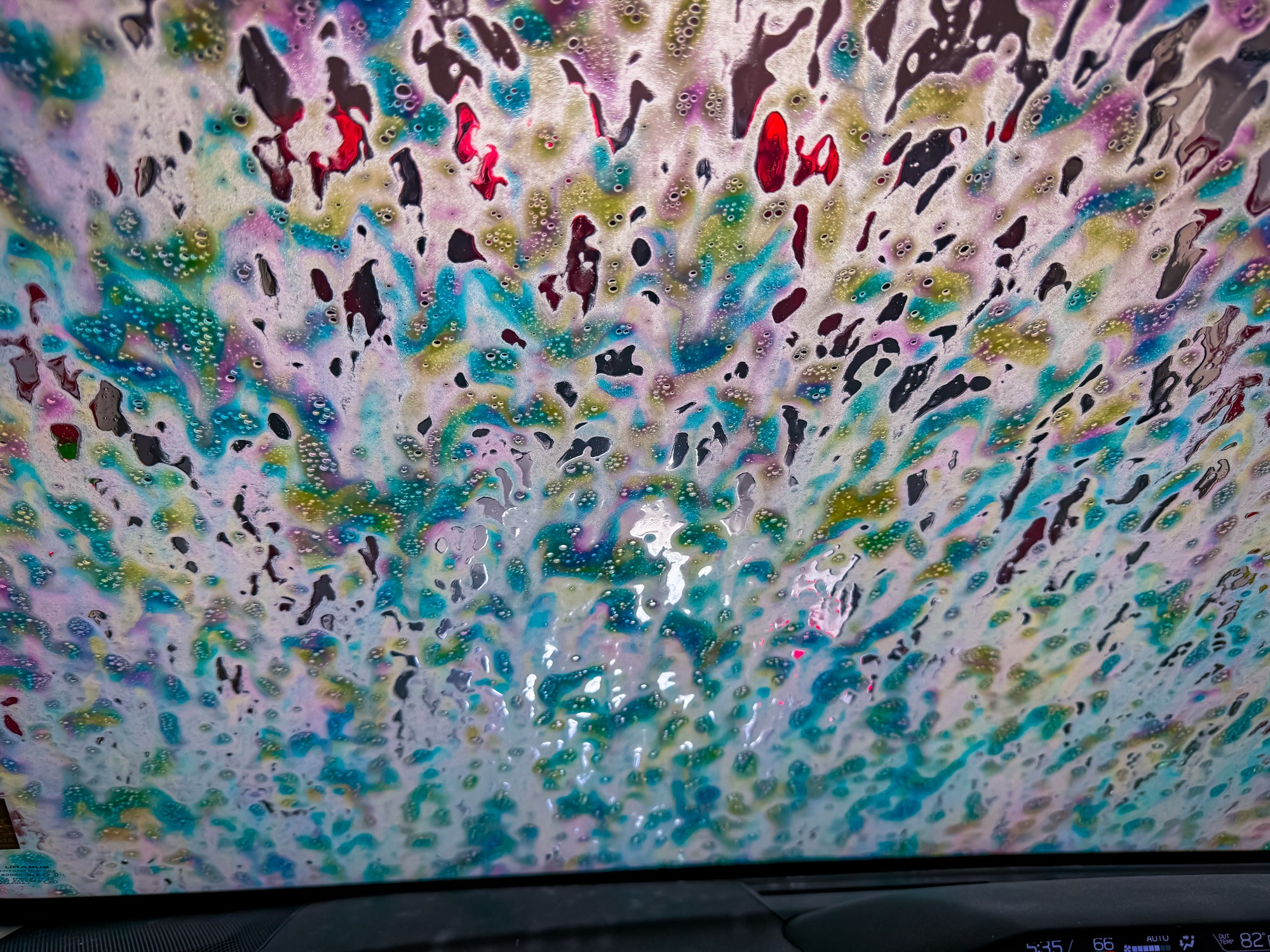 Image of a windshield with colorful foam splattered all over it.
