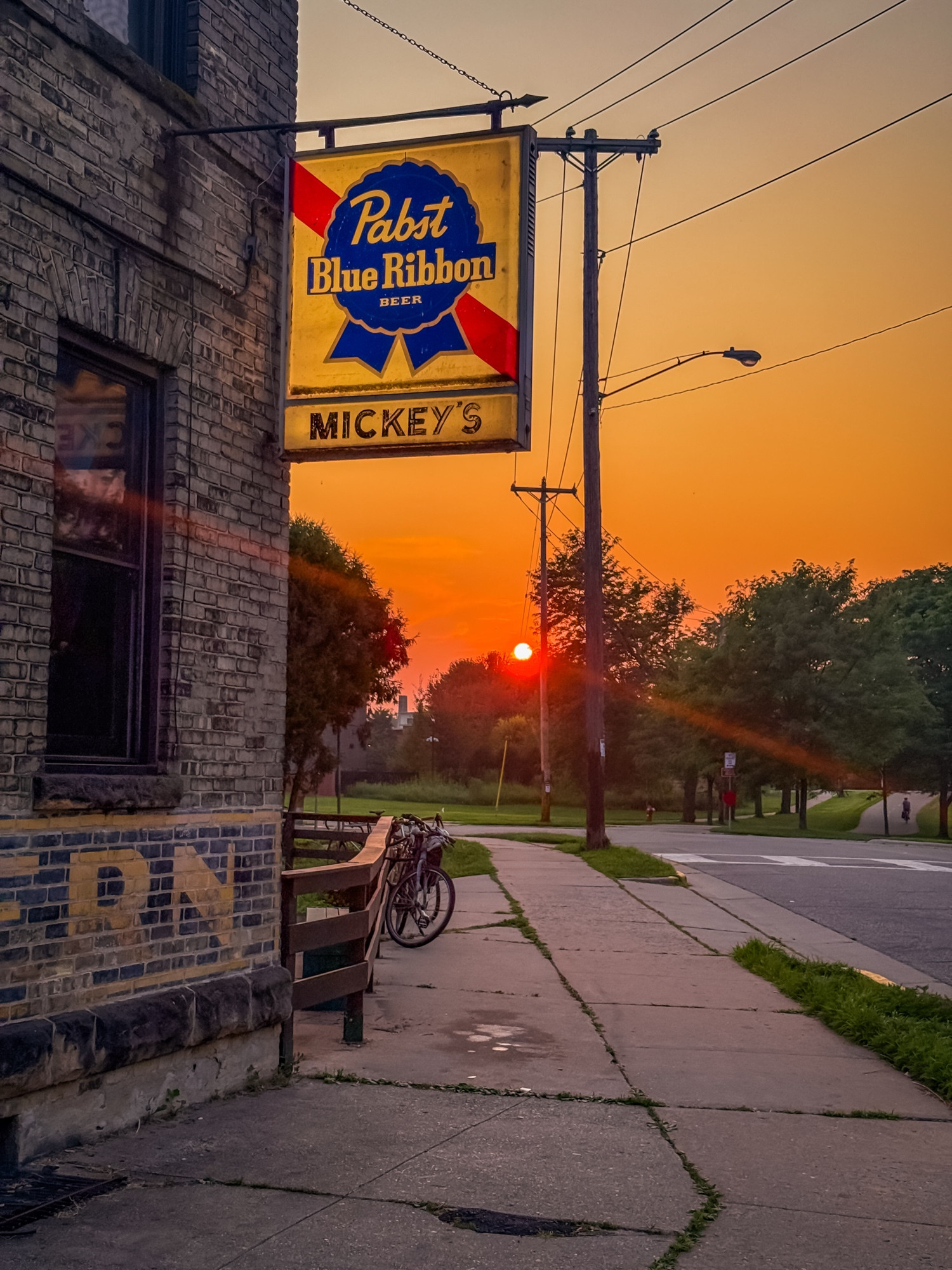 Image of a bar sign that reads “Mickey’s” against a sunset background.  The sun is very red from the haze of wildfire smoke that has drifted down from Canada.
