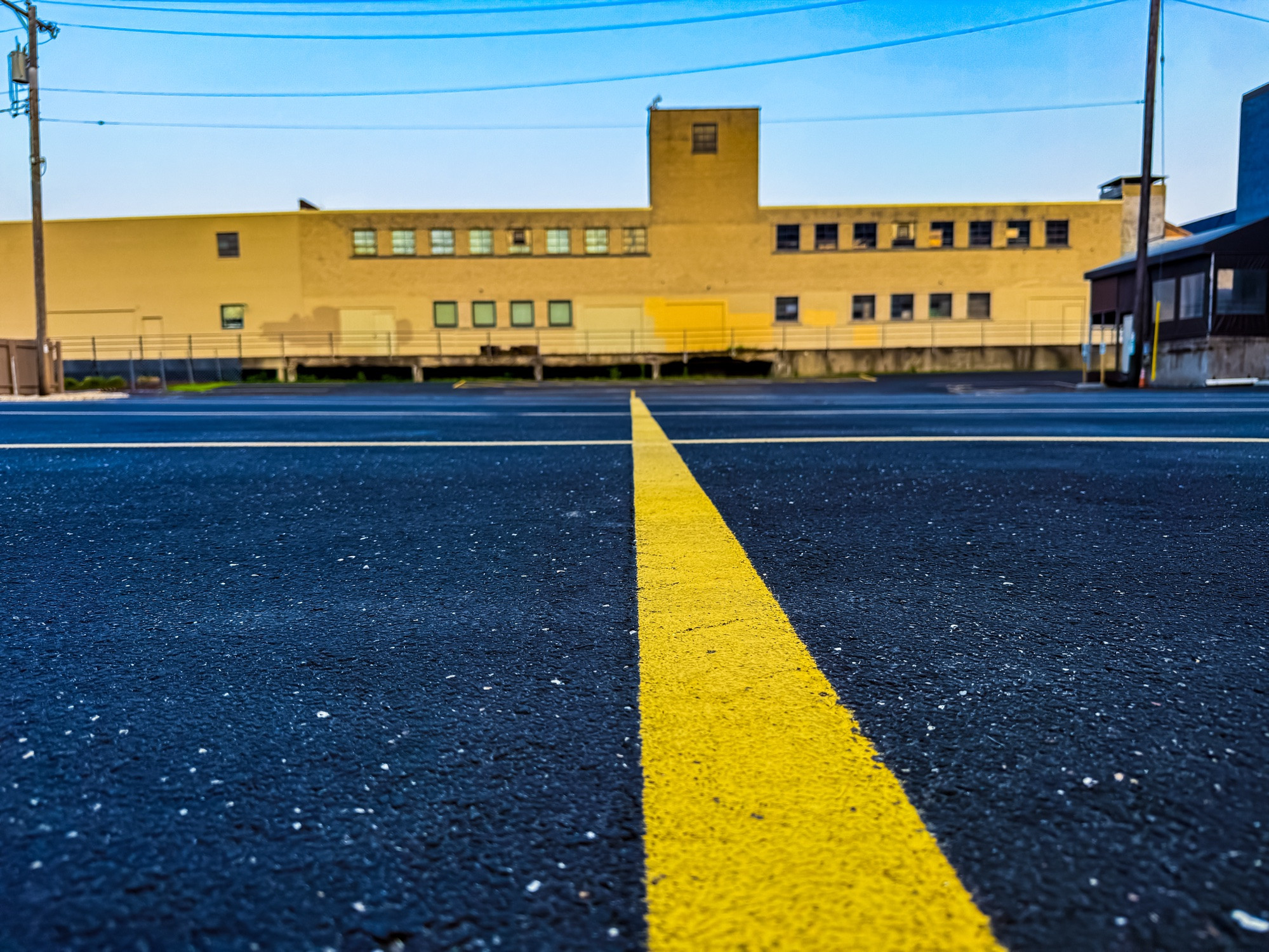 Image of a parking lot leading to an industrial building.  One of the painted yellow lines serves as a leading line into the scene.