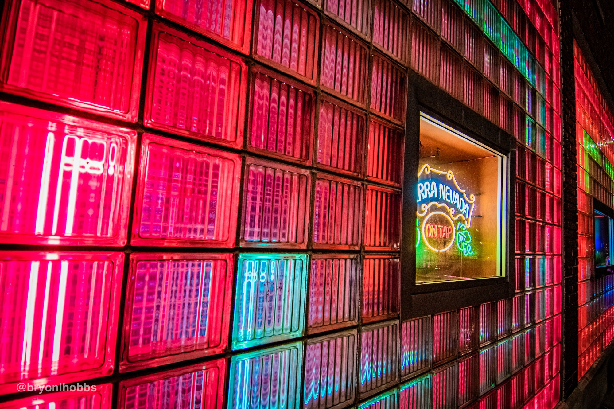 Image of a “window” of glass blocks lit up by neon lights at a side angle 