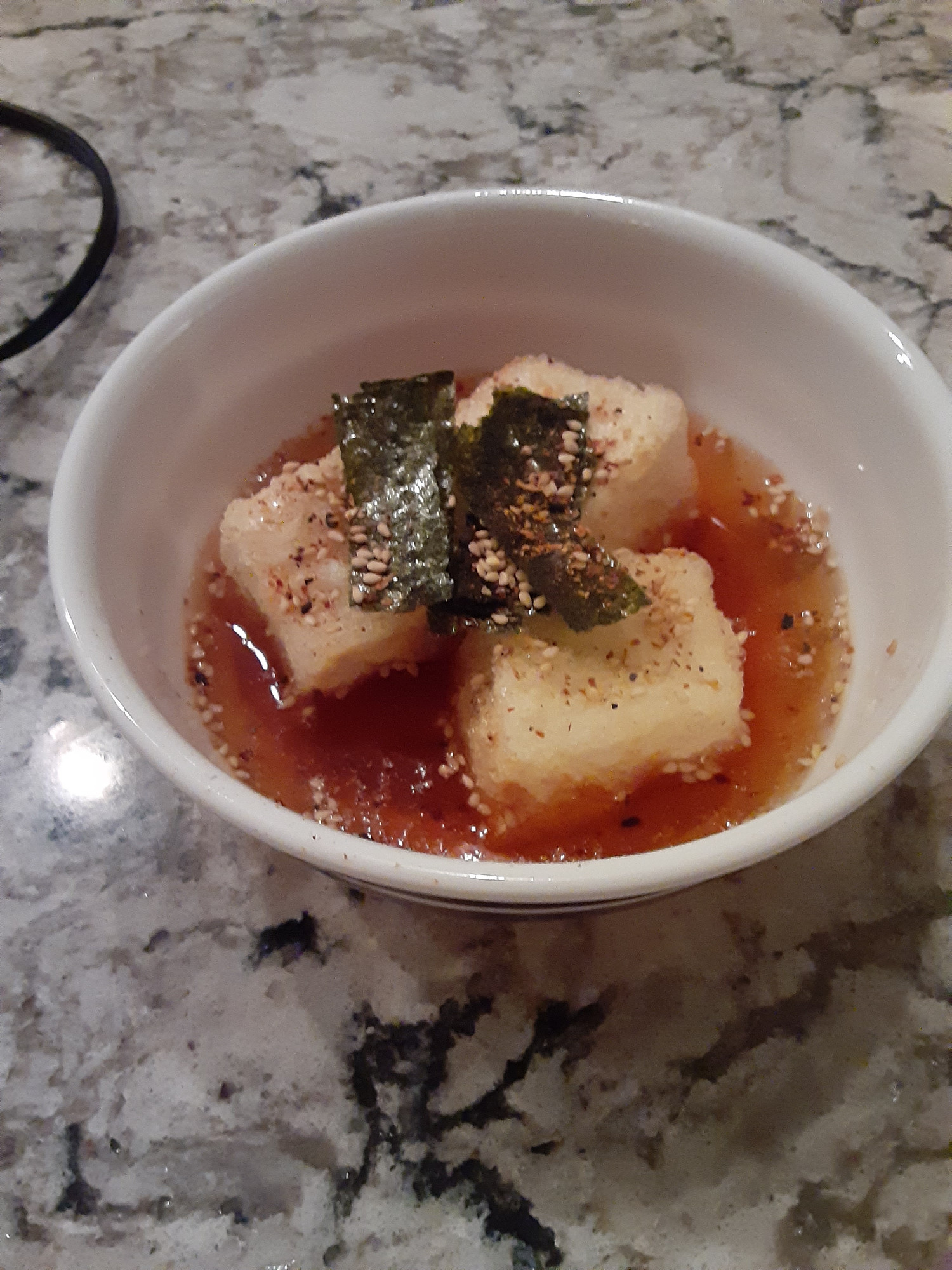 agedashi tofu (soft tofu cubes fried in potato starch and put in dashi broth) topped with sesame seeds, spice and dried seaweed