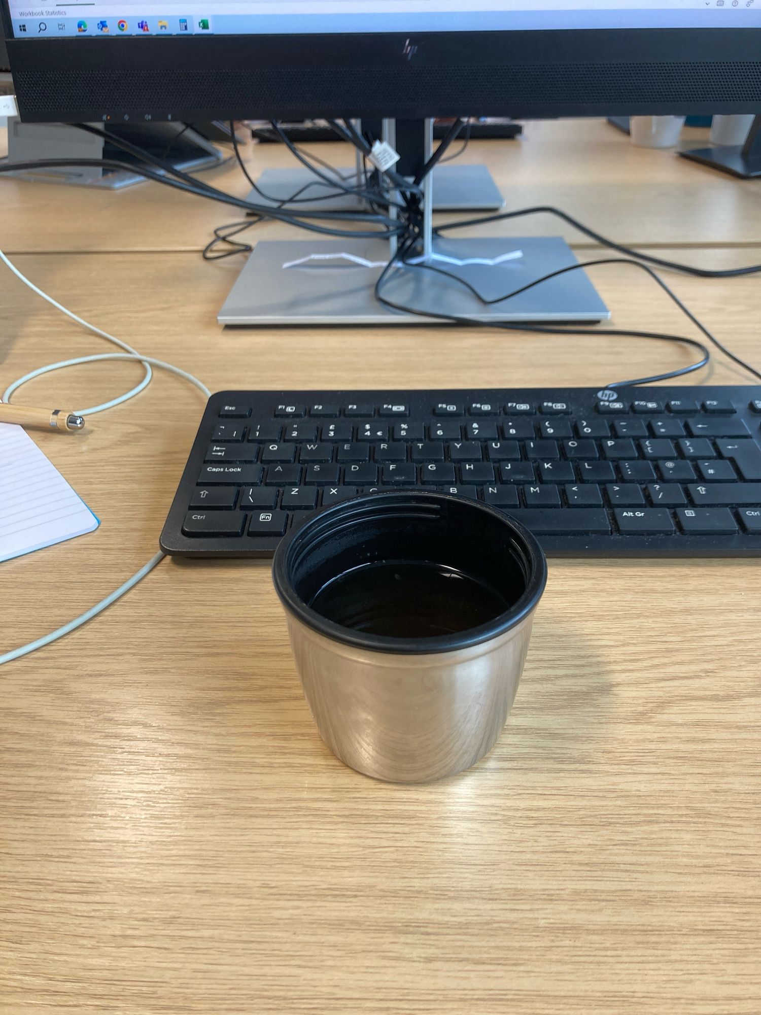 Thermos cup and PC keyboard on a desk