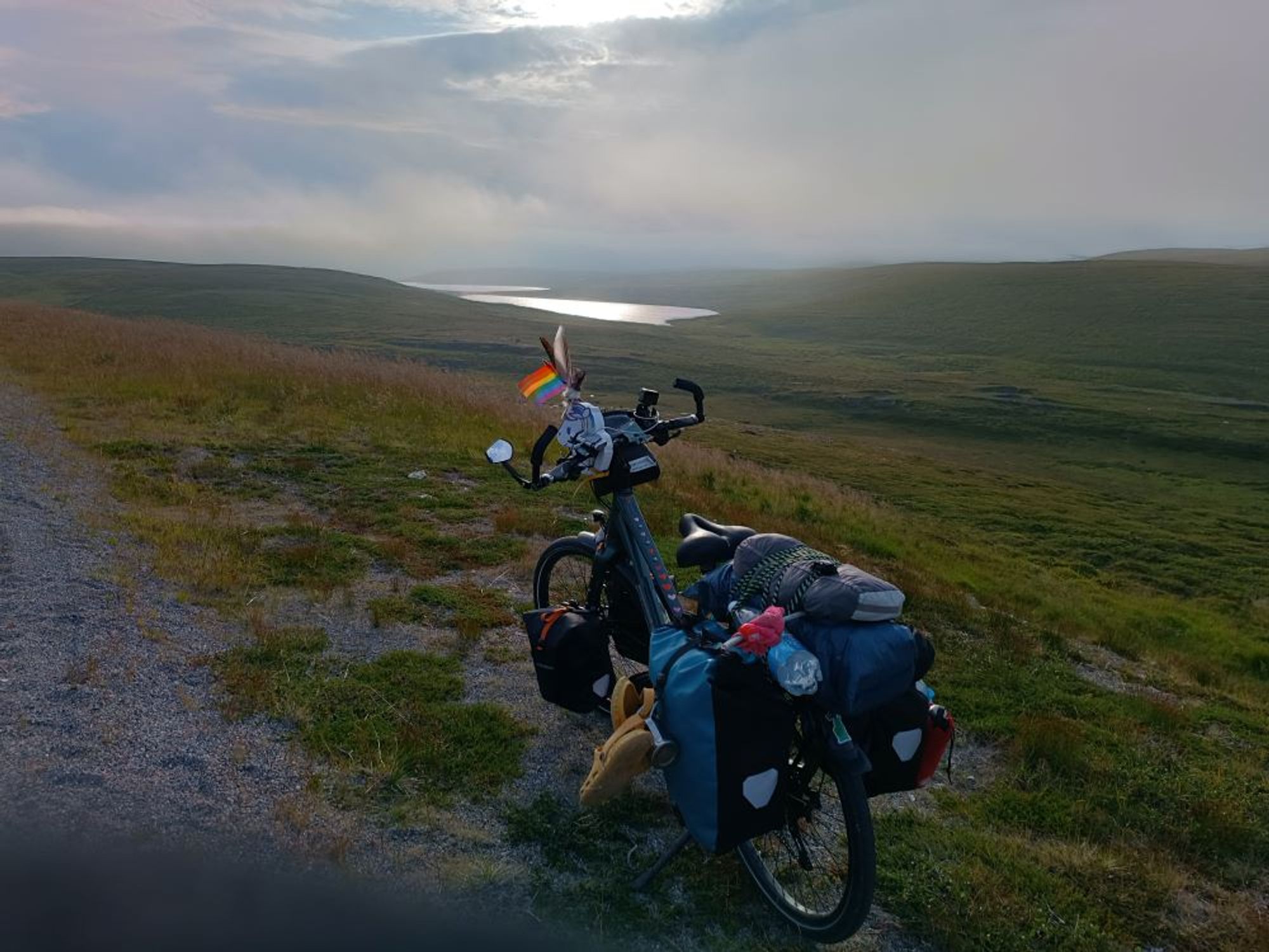 mein Reiserad steht nahe Nordkapp in einer Nachtsonnenlandschaft, flaches Land, grün, hinten ein See