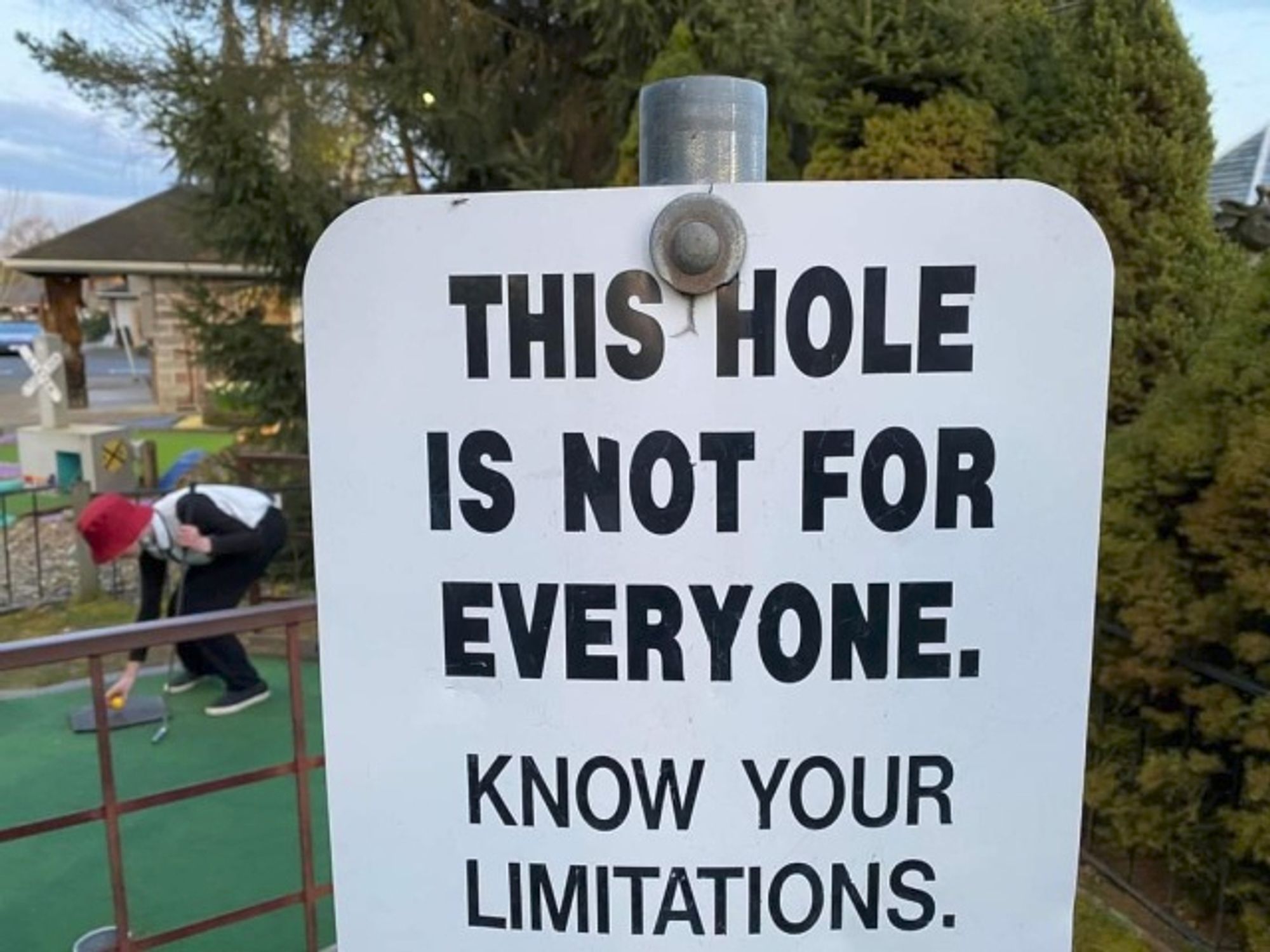 A sign reading "THIS HOLE IS NOT FOR EVERYONE. KNOW YOUR LIMITATIONS."