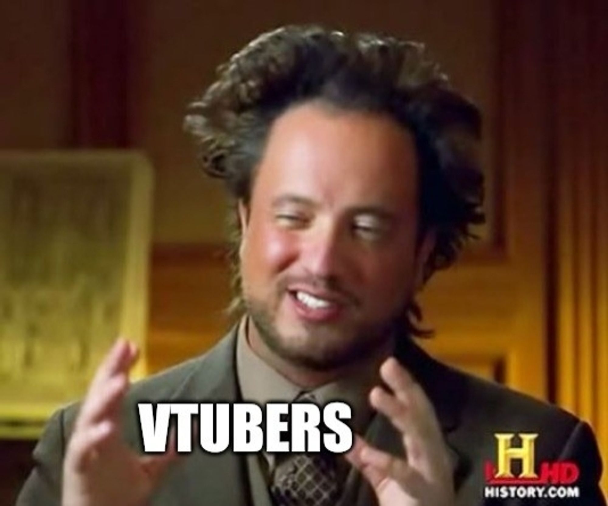 A man from the TV show Ancient Aliens holding his hands up, smirking, with the word "Vtubers" between his hands.