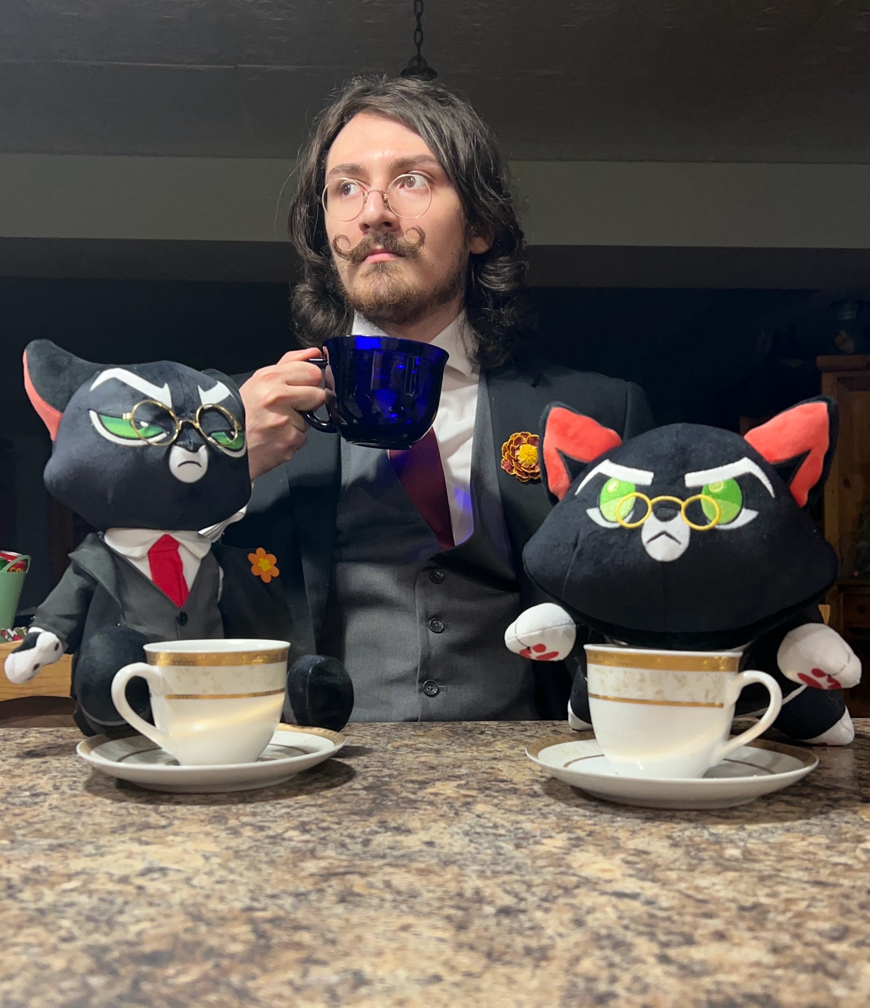 Image shows someone cosplaying as Mordecai Heller from webcomic/animated series Lackadaisy, accompanied by two plushes of the same character all drinking tea