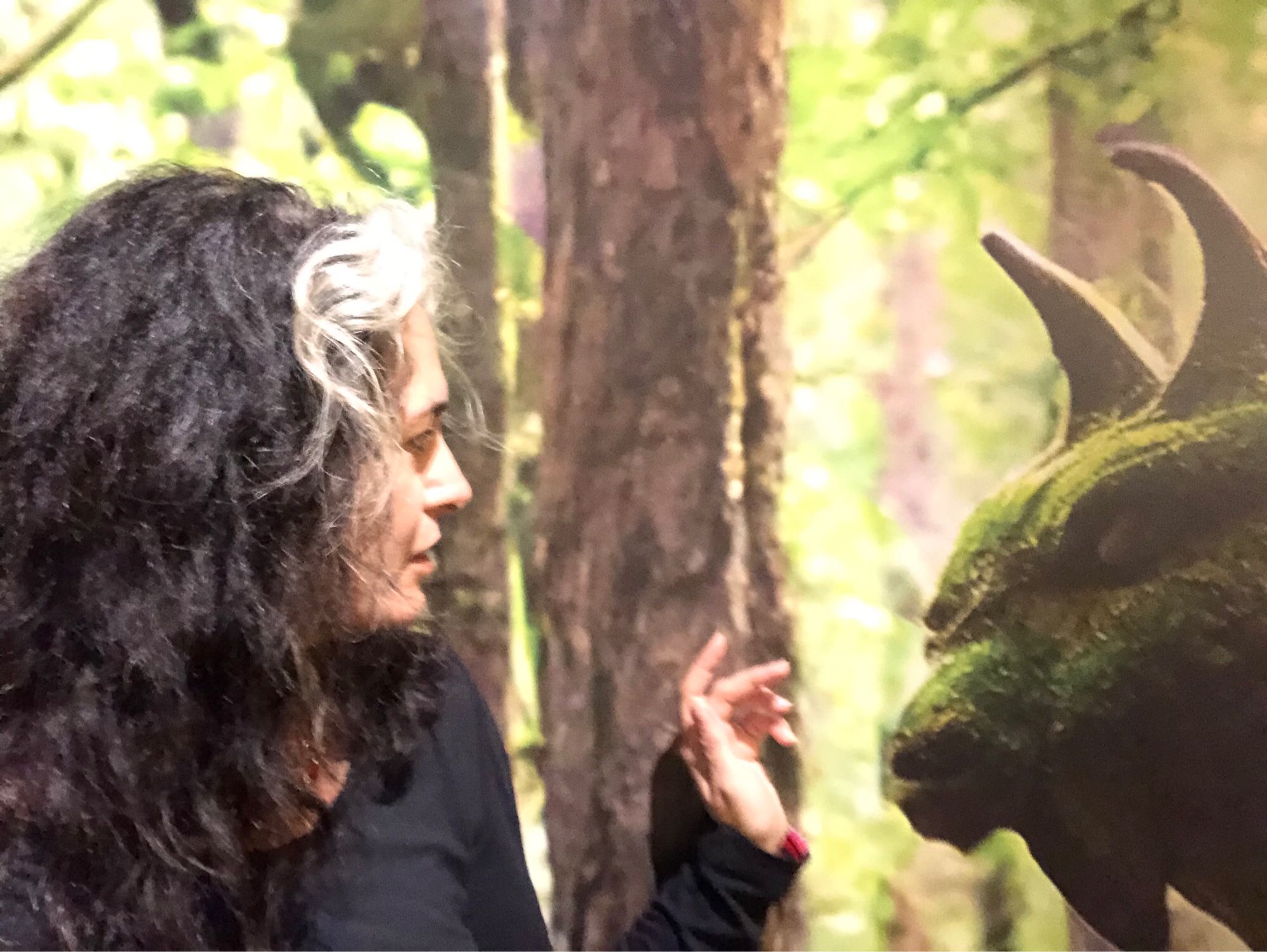 Pen tentatively reaching out to touch an overgrown gargoyle statue in a wood