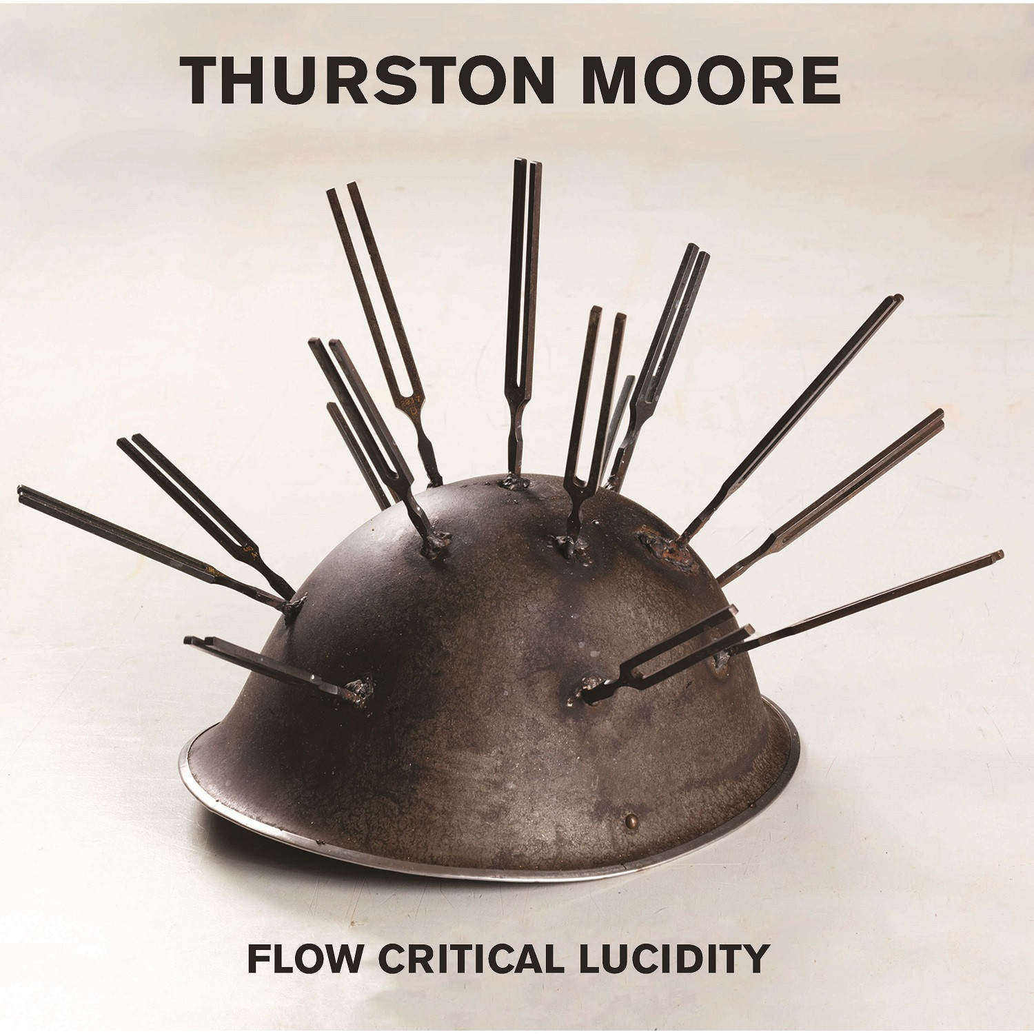 Thurston Moore - Flow Critical Lucidity album artwork.

Un casque de métal avec plusieurs diapasons soudés dessus, pointant vers l'extérieur.