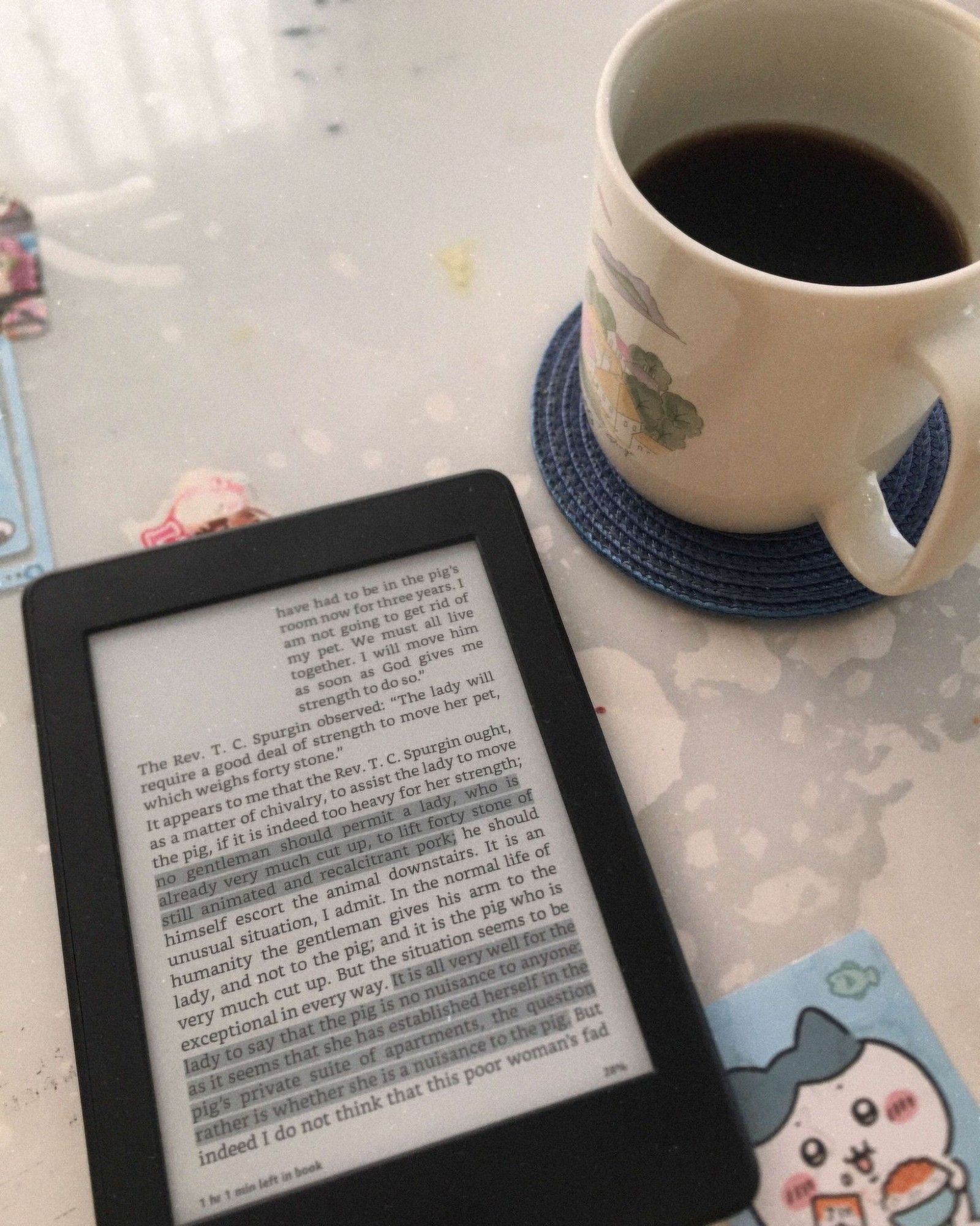 Kindle E-reader showing a page with some highlighted text beside a cup of coffee.