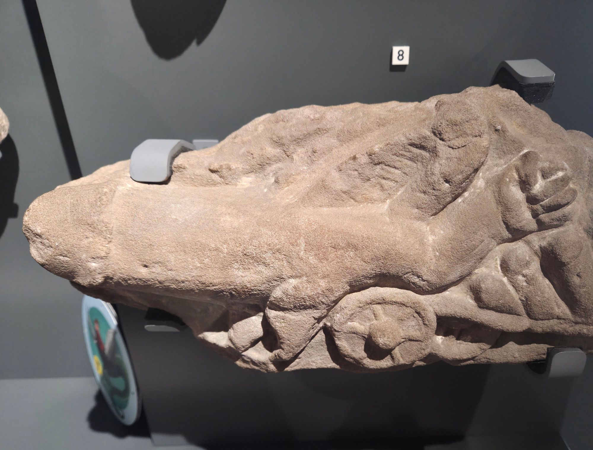 A carving of a winged phallus complete with arm and fist which seems to be pulling a cart. Roman in origin.