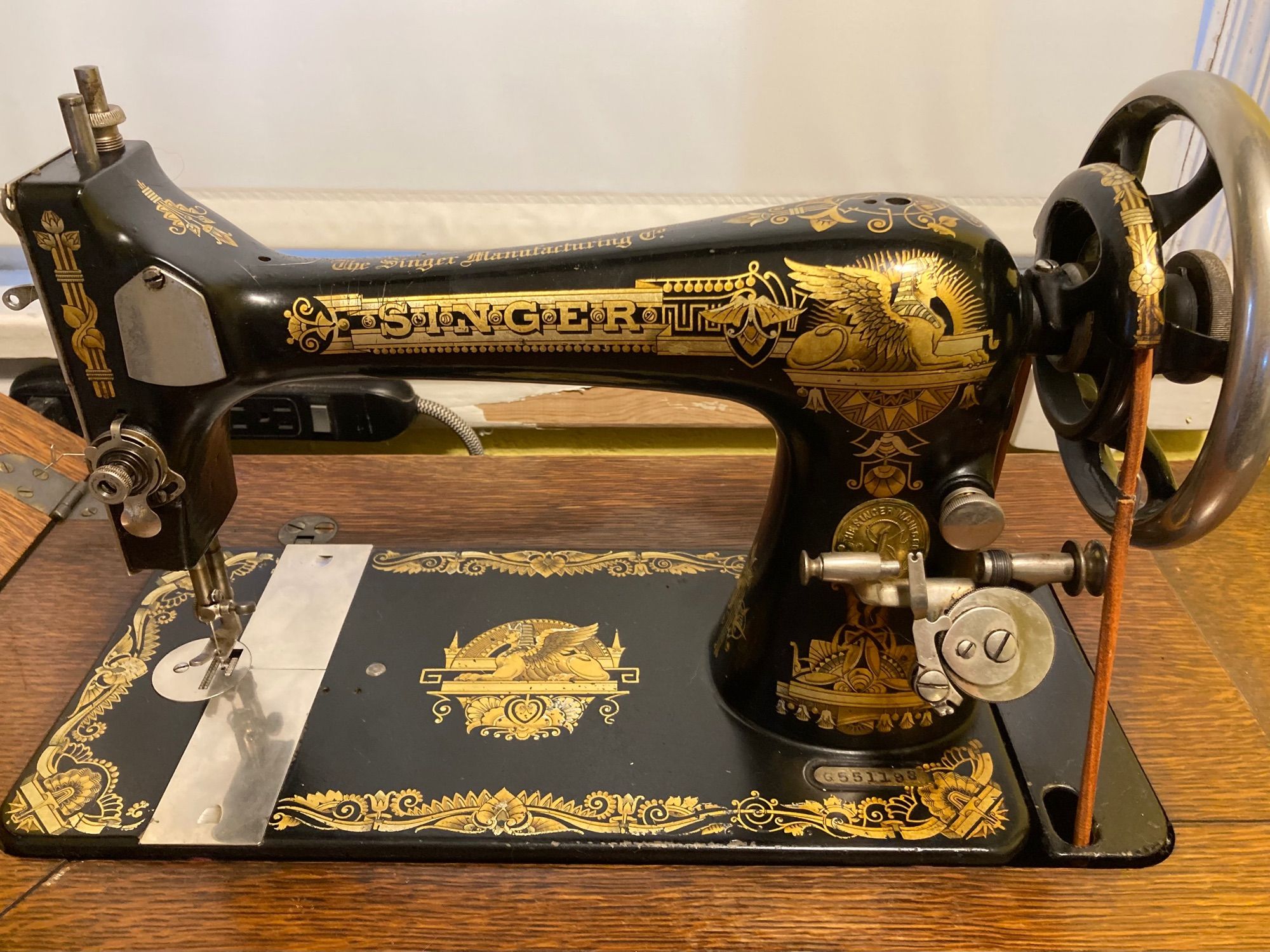 An antique Singer treadle sewing machine head. The machine is black and lavishly decorated with Egyptian-influenced designs in gold.

The machine is in its cabinet, but most of the cabinet not in the photo.