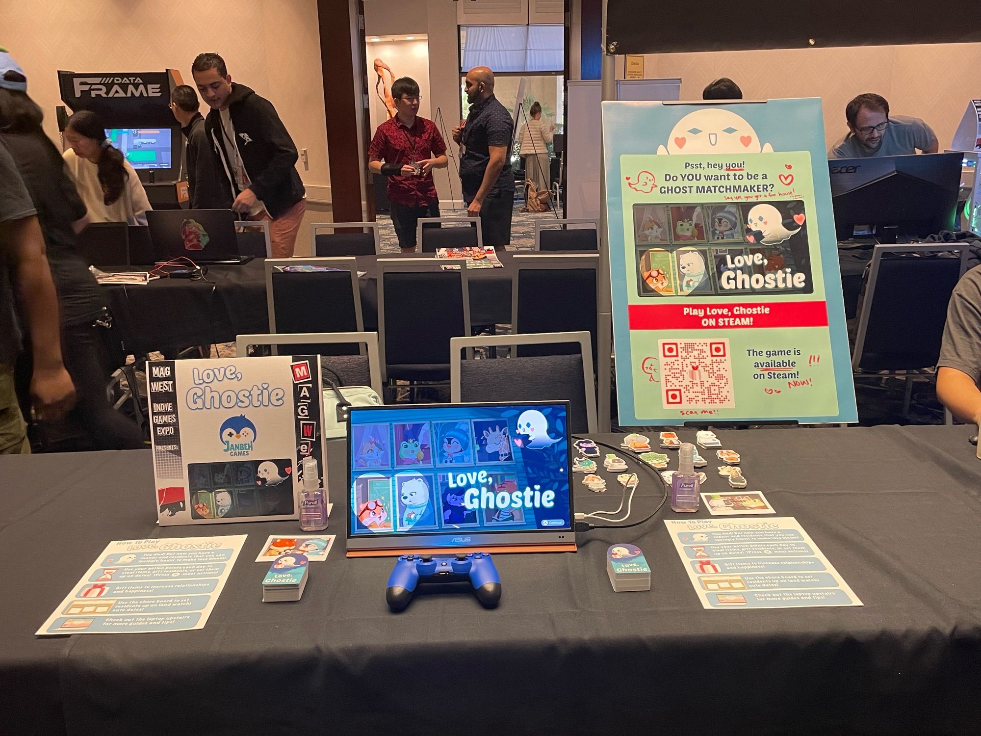 Picture of table set up of Love, Ghostie with a sign, monitor, controller, and stickers