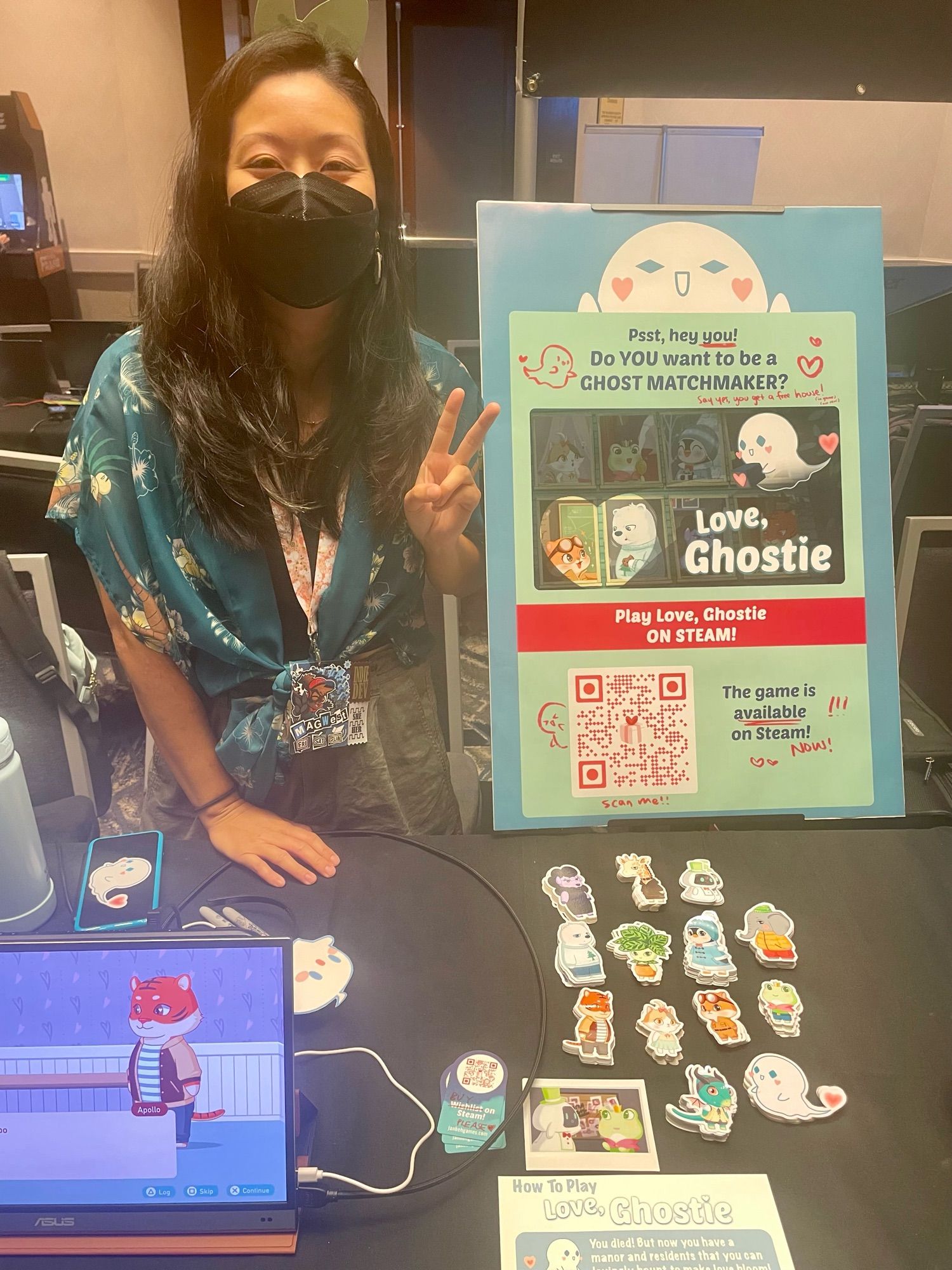 Picture of me at the table at MAGWest standing near a Love, Ghostie poster